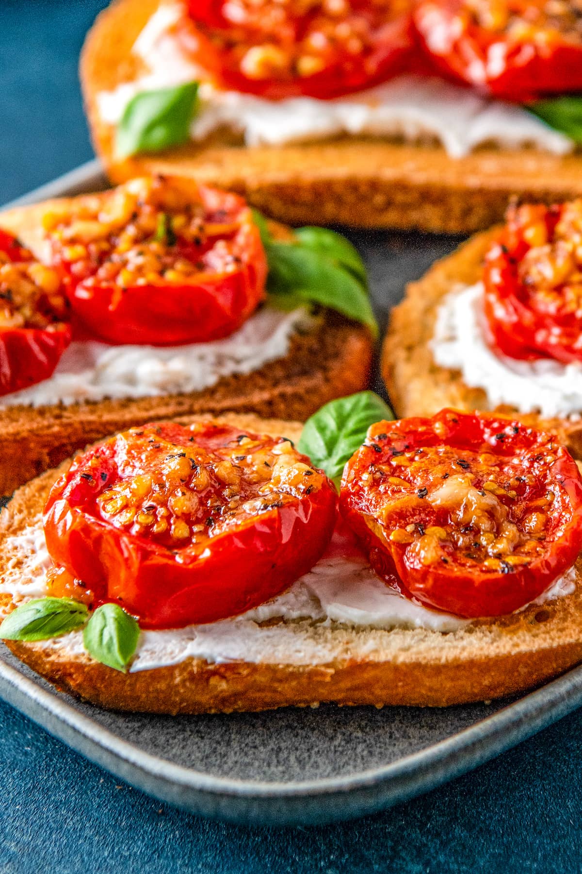 roasted tomatoes on pieces of toast on top of a cream spread