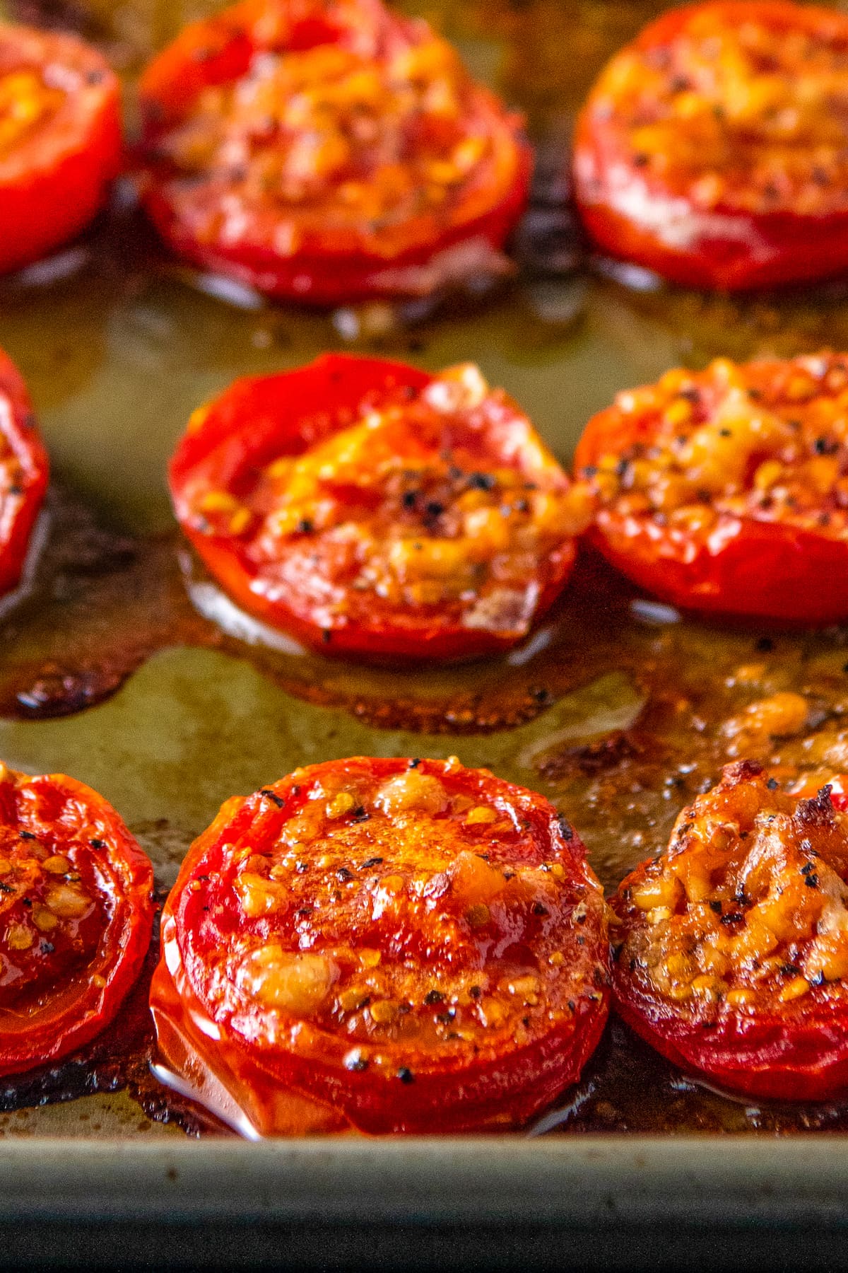 sliced roasted tomatoes on a sheet tray with seasonings and oil