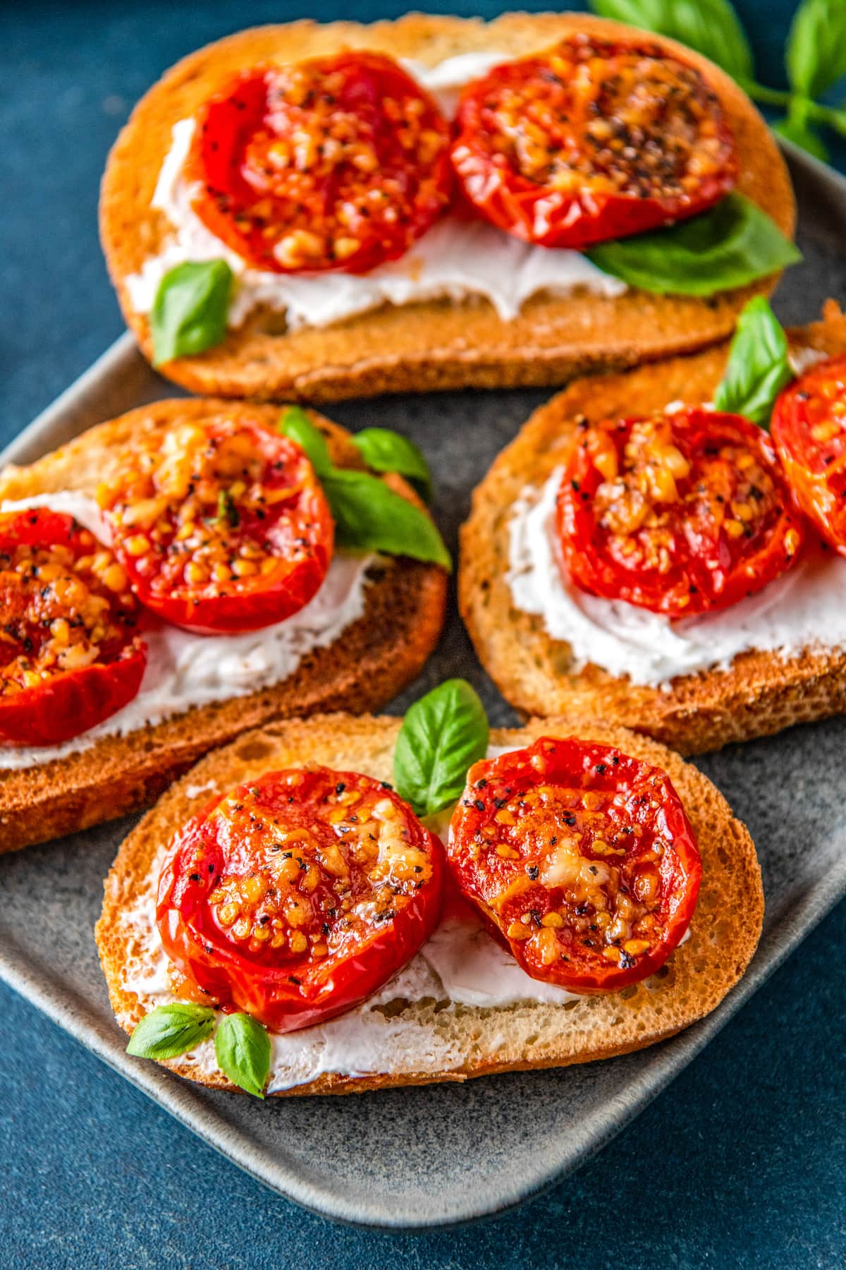 roasted tomatoes on pieces of toast on top of a cream spread