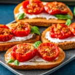 roasted tomatoes on pieces of toast on top of a cream spread