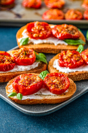 roasted tomatoes on pieces of toast on top of a cream spread