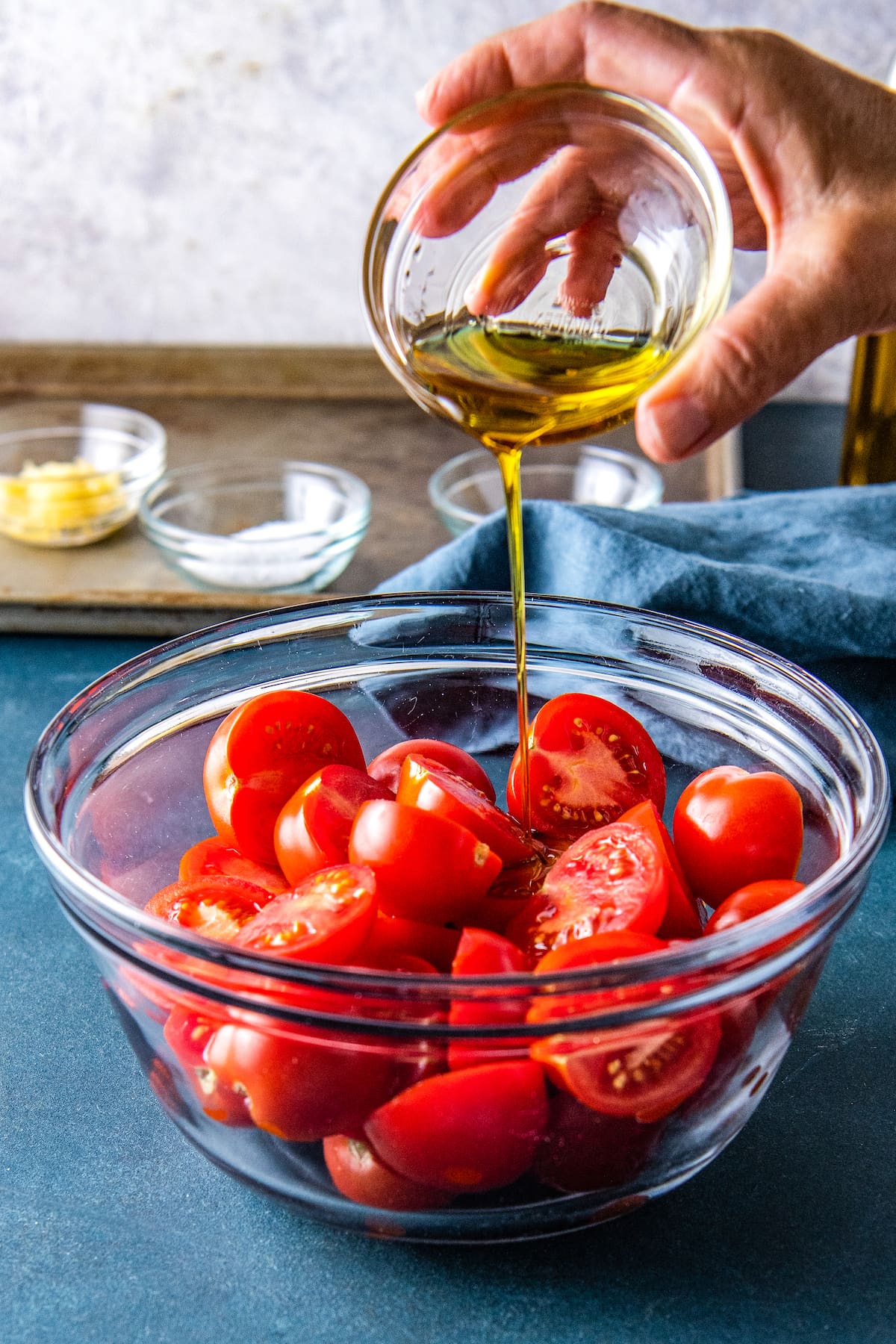 a bowl with cut up tomatoes and being seasoned with oil