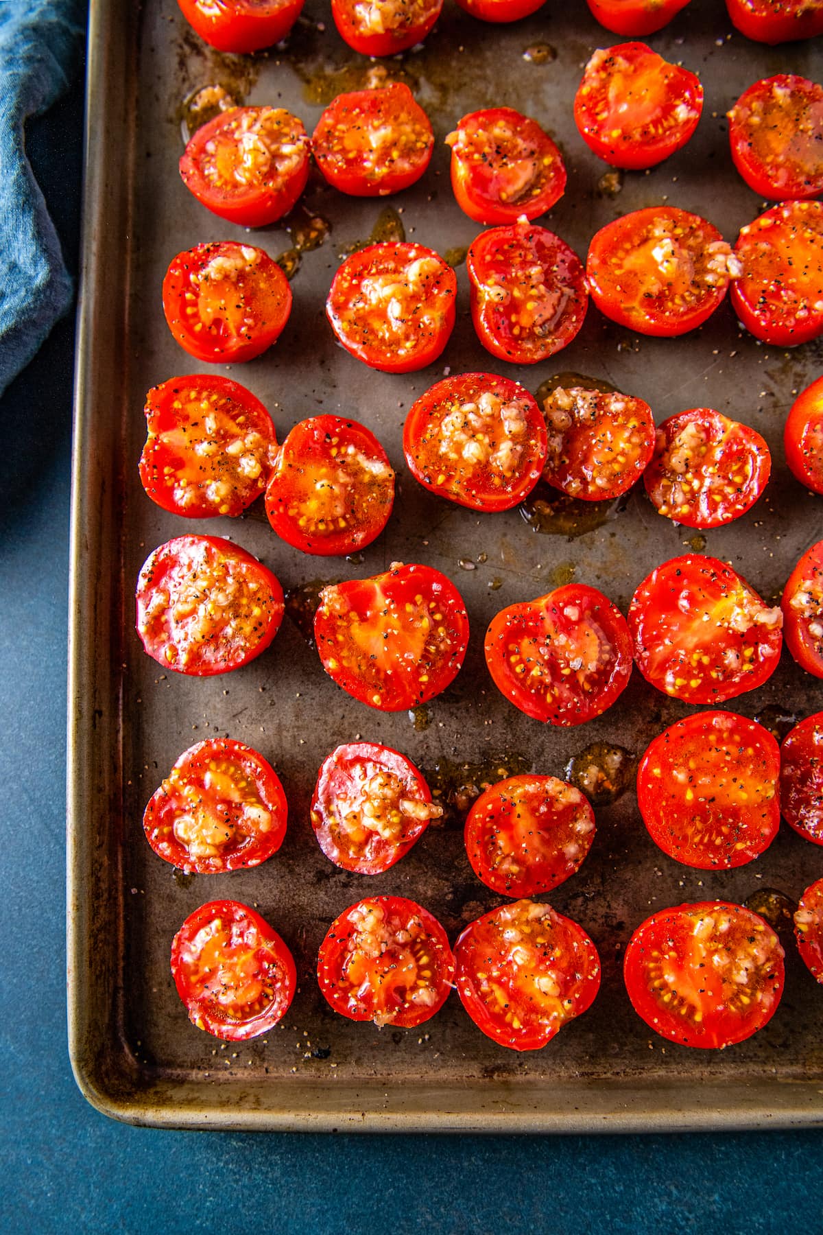 sliced tomatoes on a sheet tray with seasonings and oil