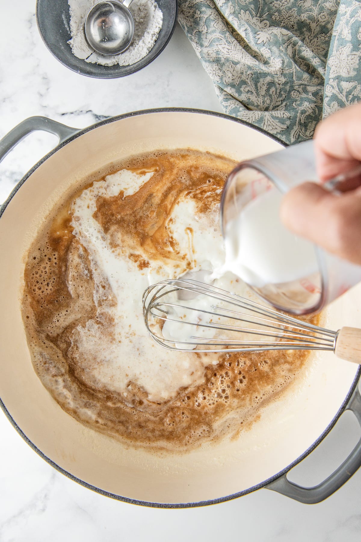 pouring milk into pot with butter and flour mixed together