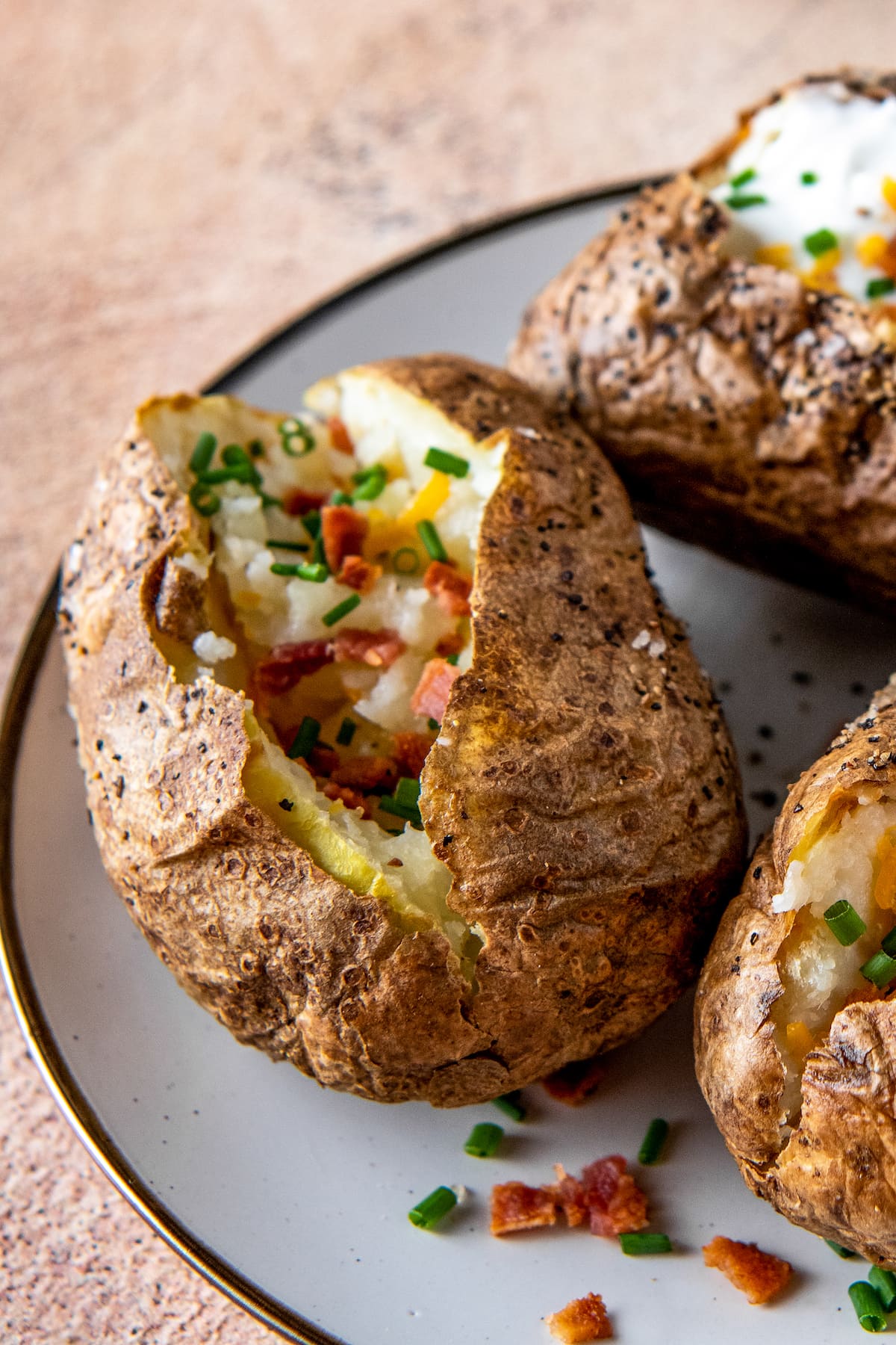 a plate with baked potatoes and cheese, bacon bits, and sour cream