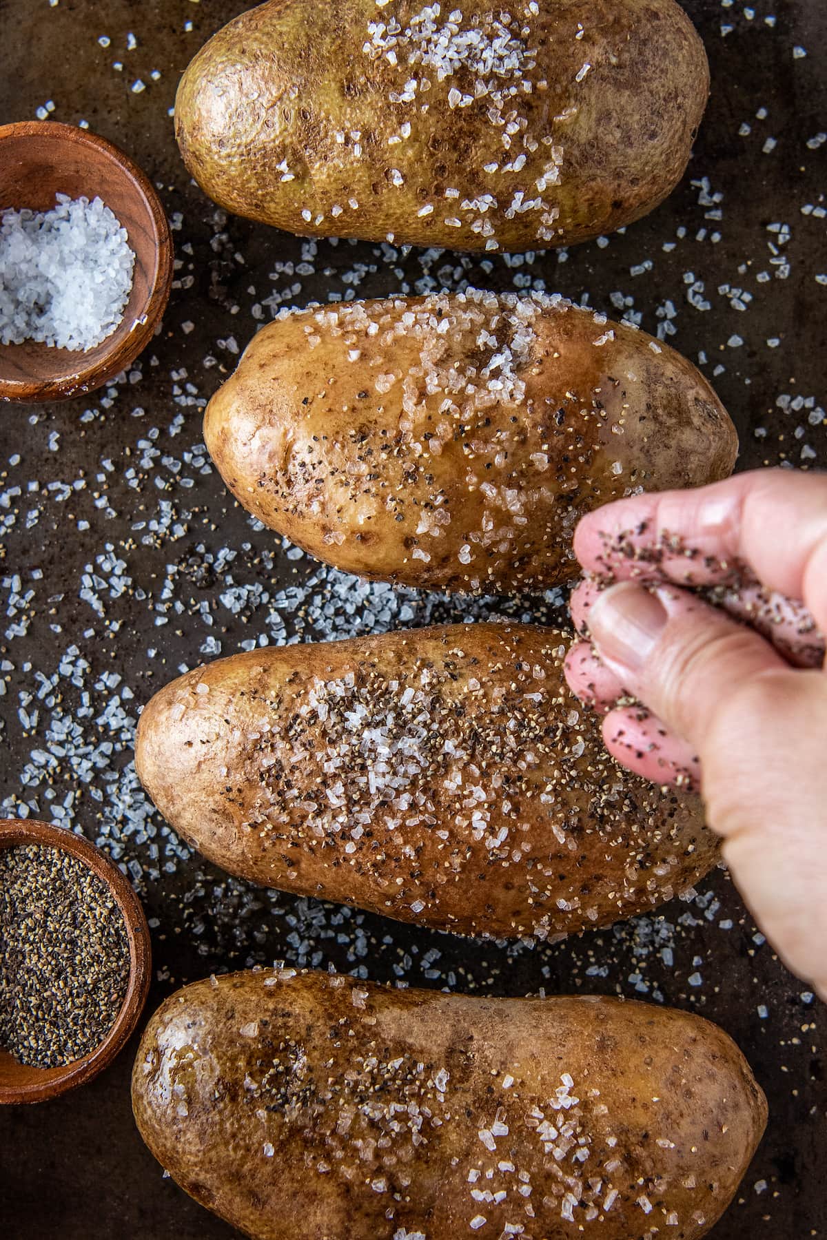 potatoes being seasoned with salt and pepper