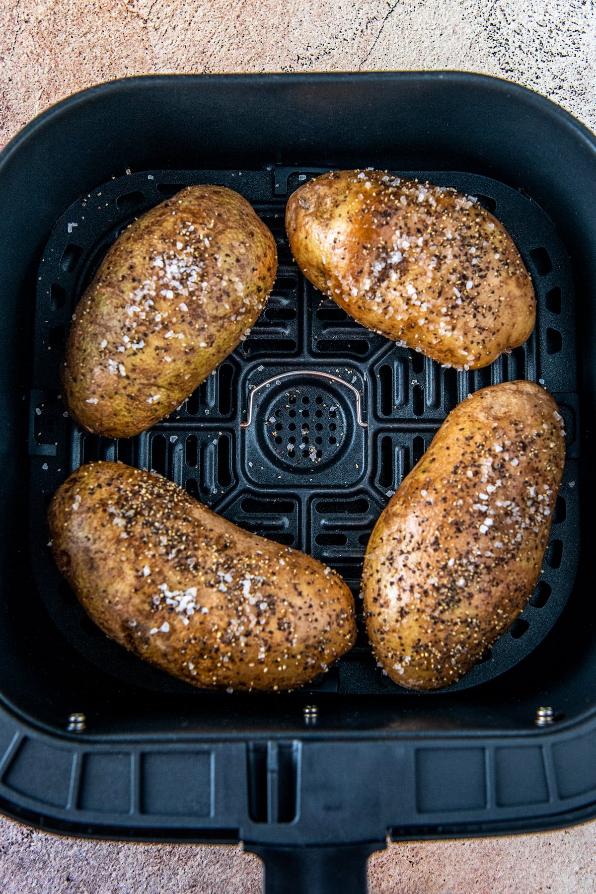 four potatoes in an air fryer tray