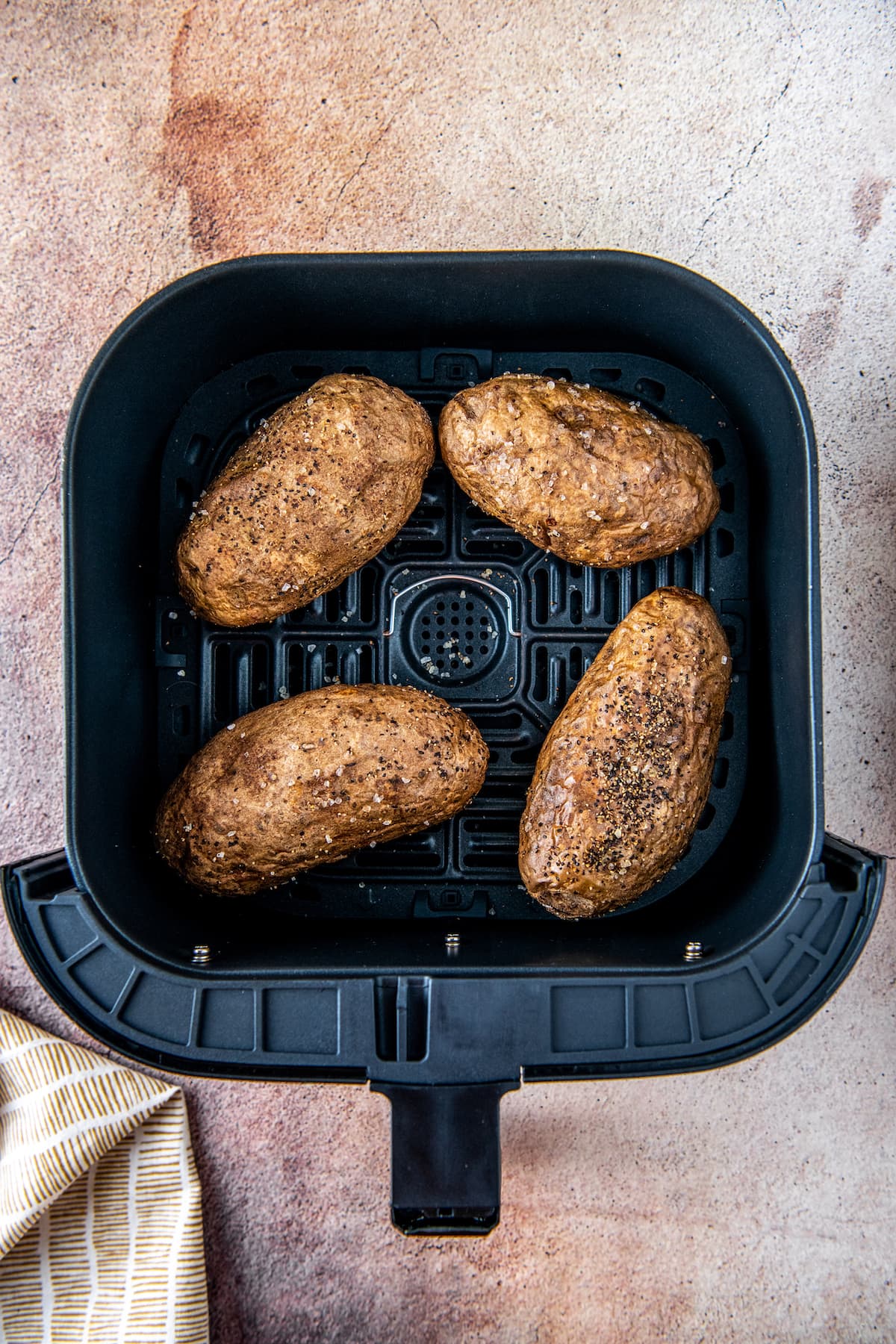 four potatoes in an air fryer tray