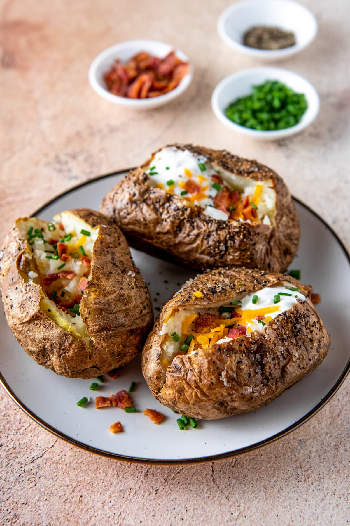 a plate with three loaded baked potatoes