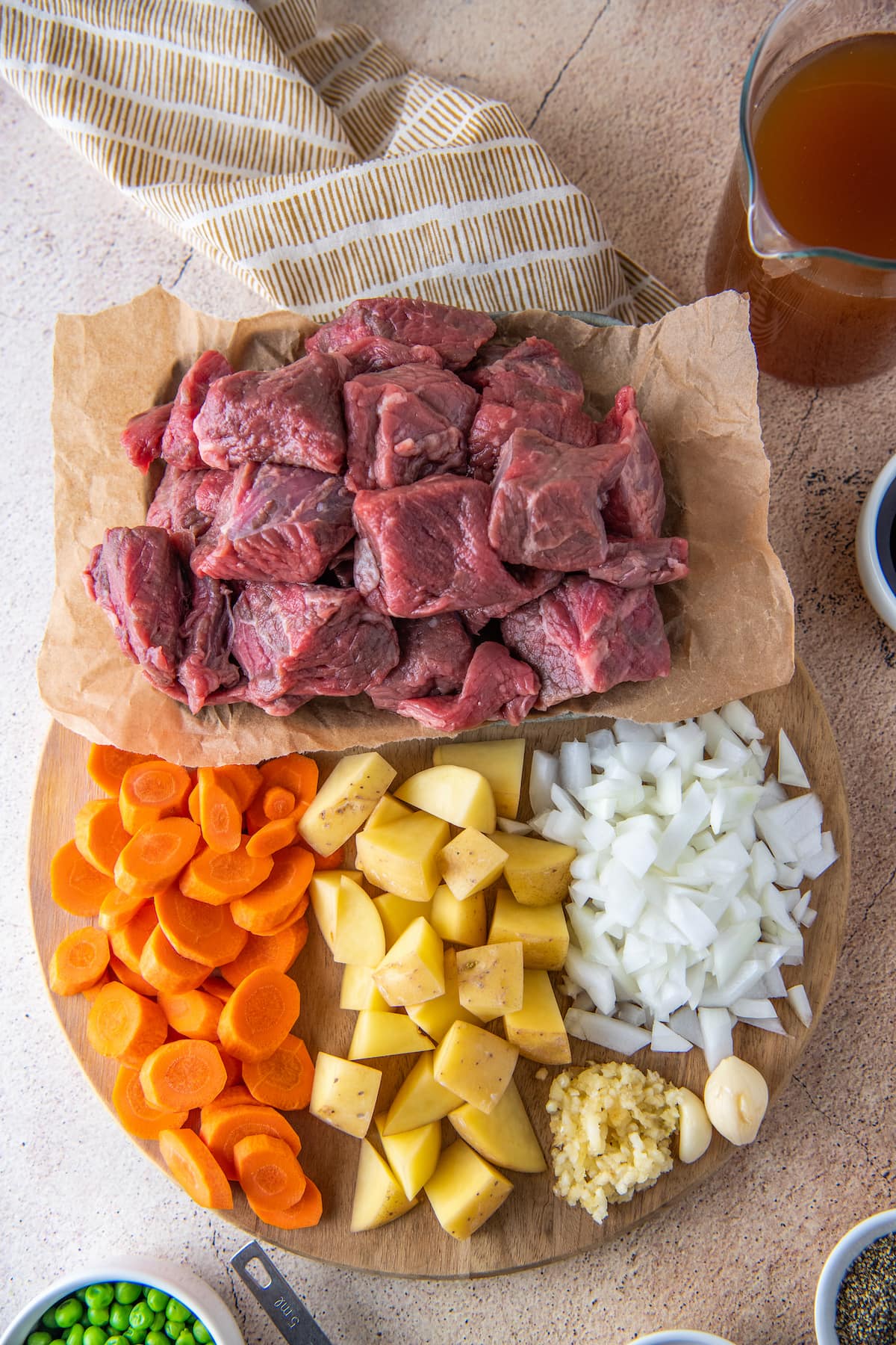 chunks of raw beer, cut up carrots, potatoes, and onions on a plate