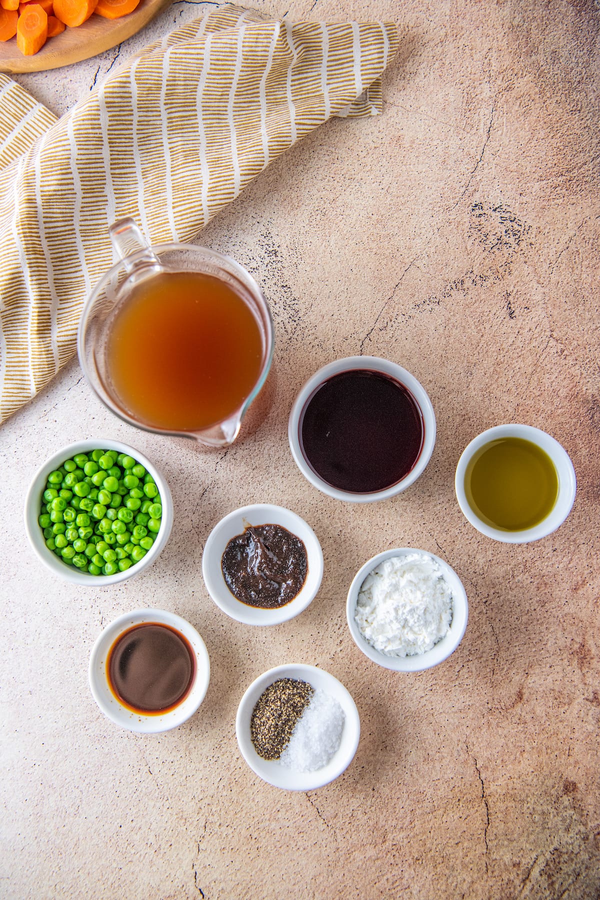 small dishes with various ingredients to make beef stew like broth, seasonings, and fresh herbs