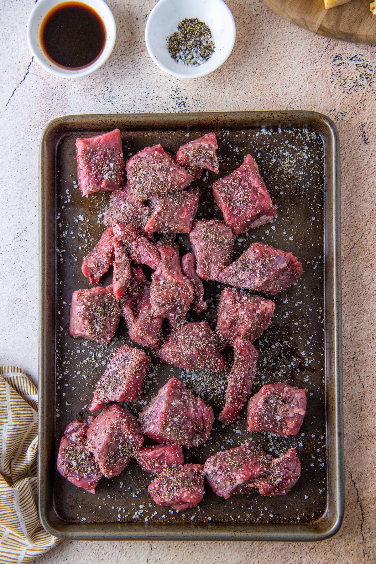 large cuts of beef seasoned on a sheet tray