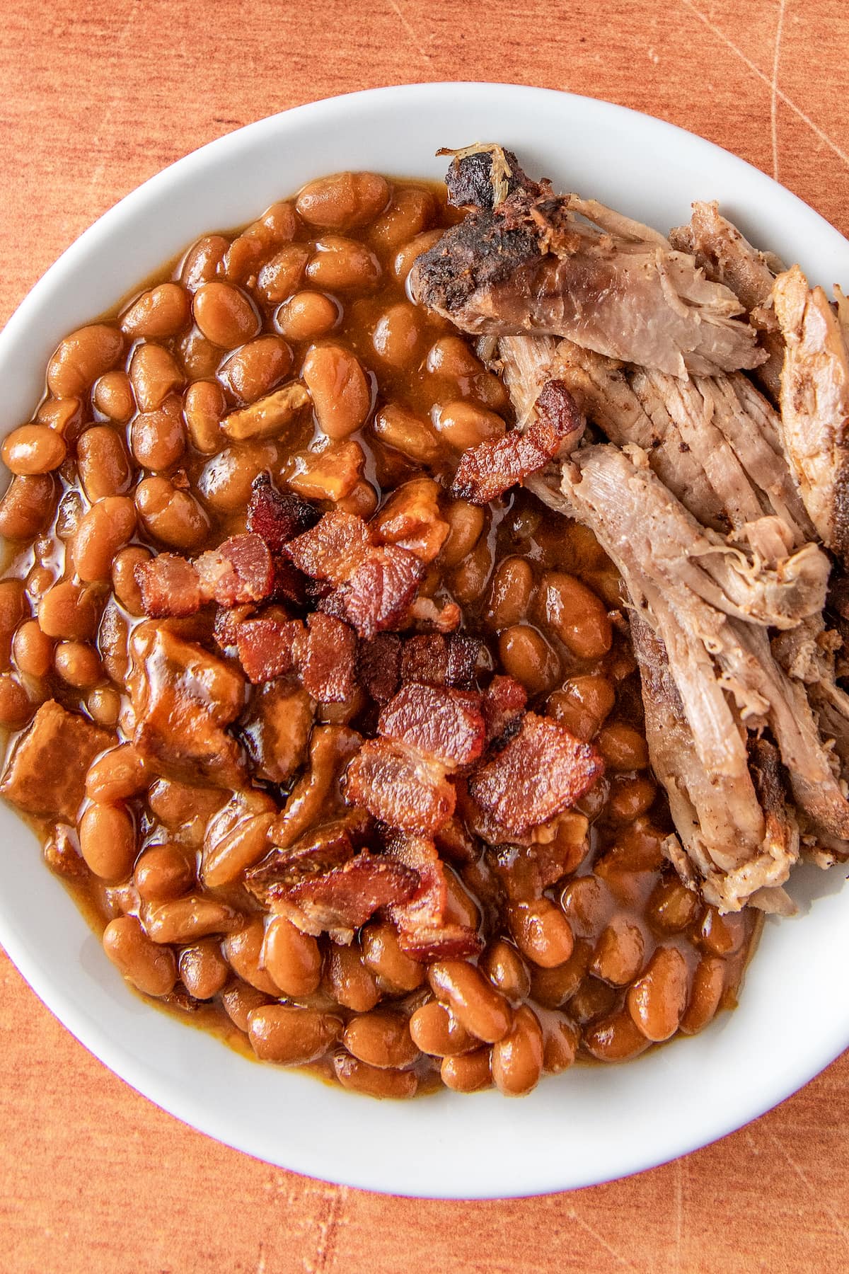 baked beans in a bowl with pulled pork on the side