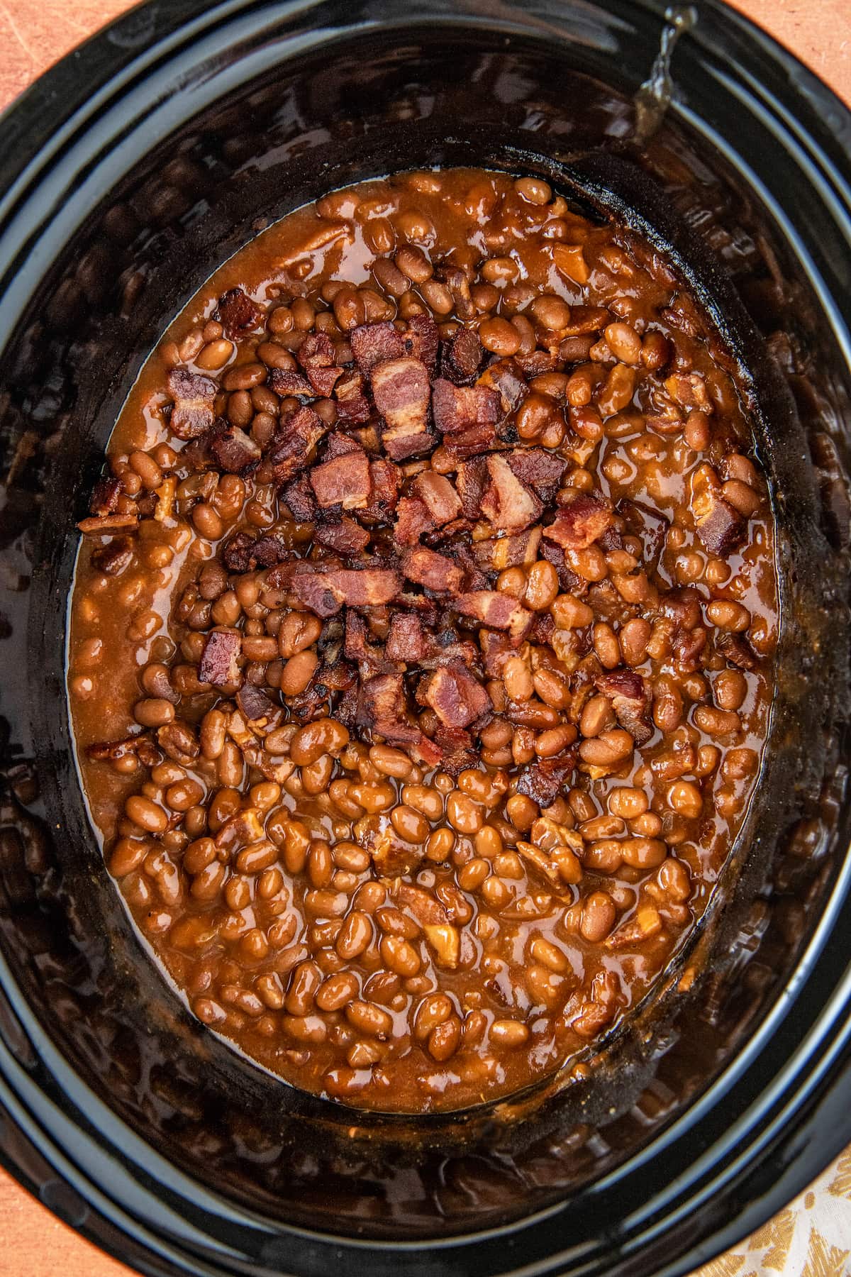 a slow cooker with baked beans and bacon pieces