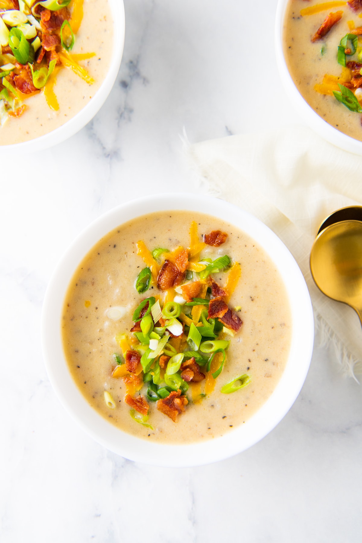 creamy potato soup with bacon, green onions, and cheese garnish