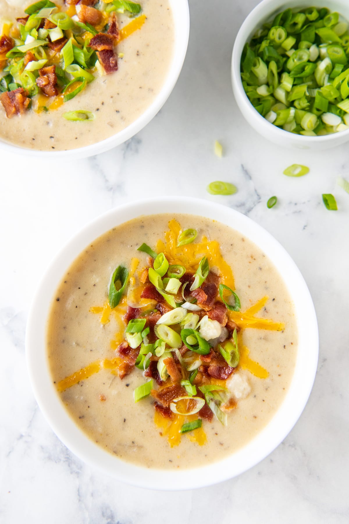 creamy potato soup with bacon, green onions, and cheese garnish