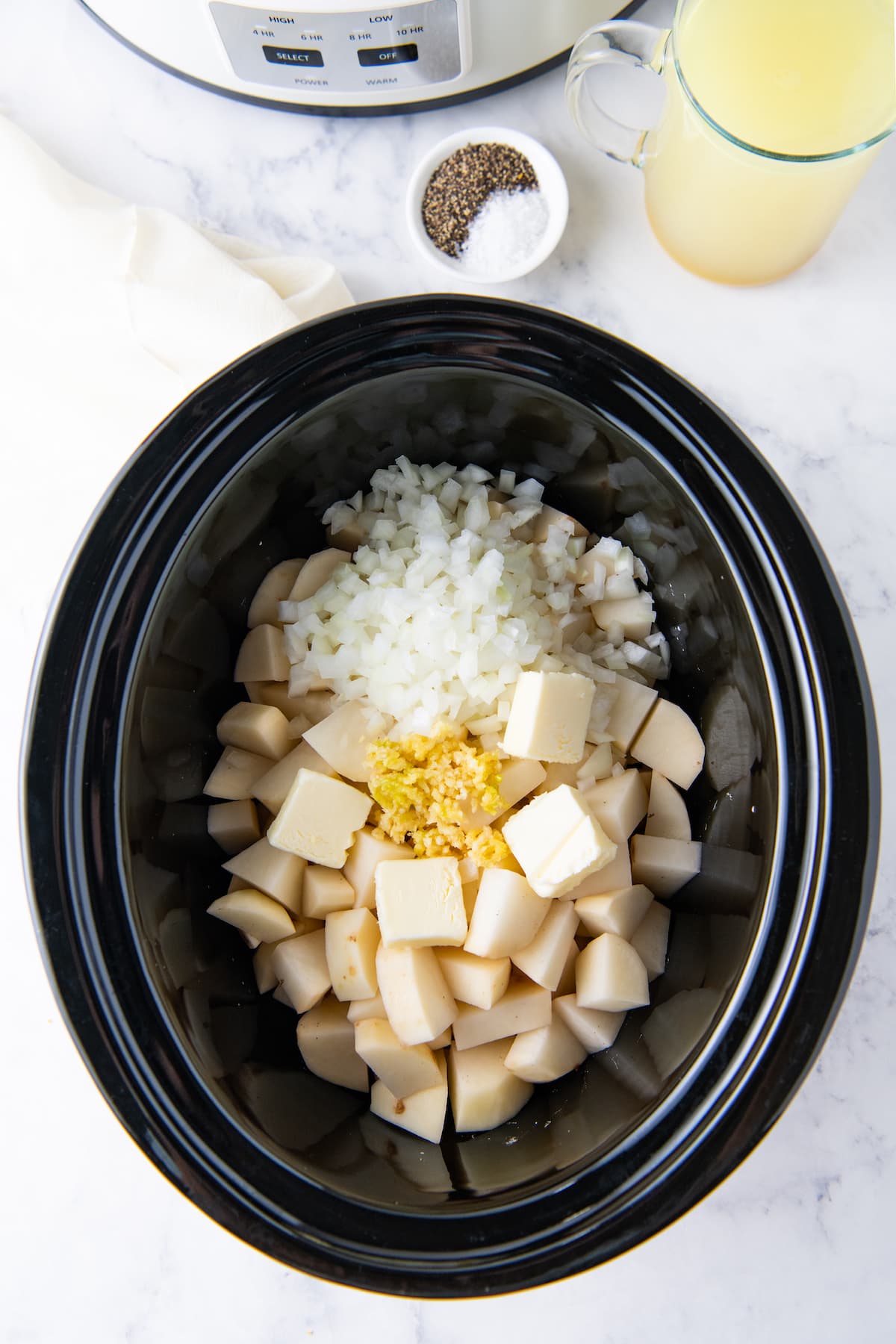 a crockpot with potatoes, onions, and butter
