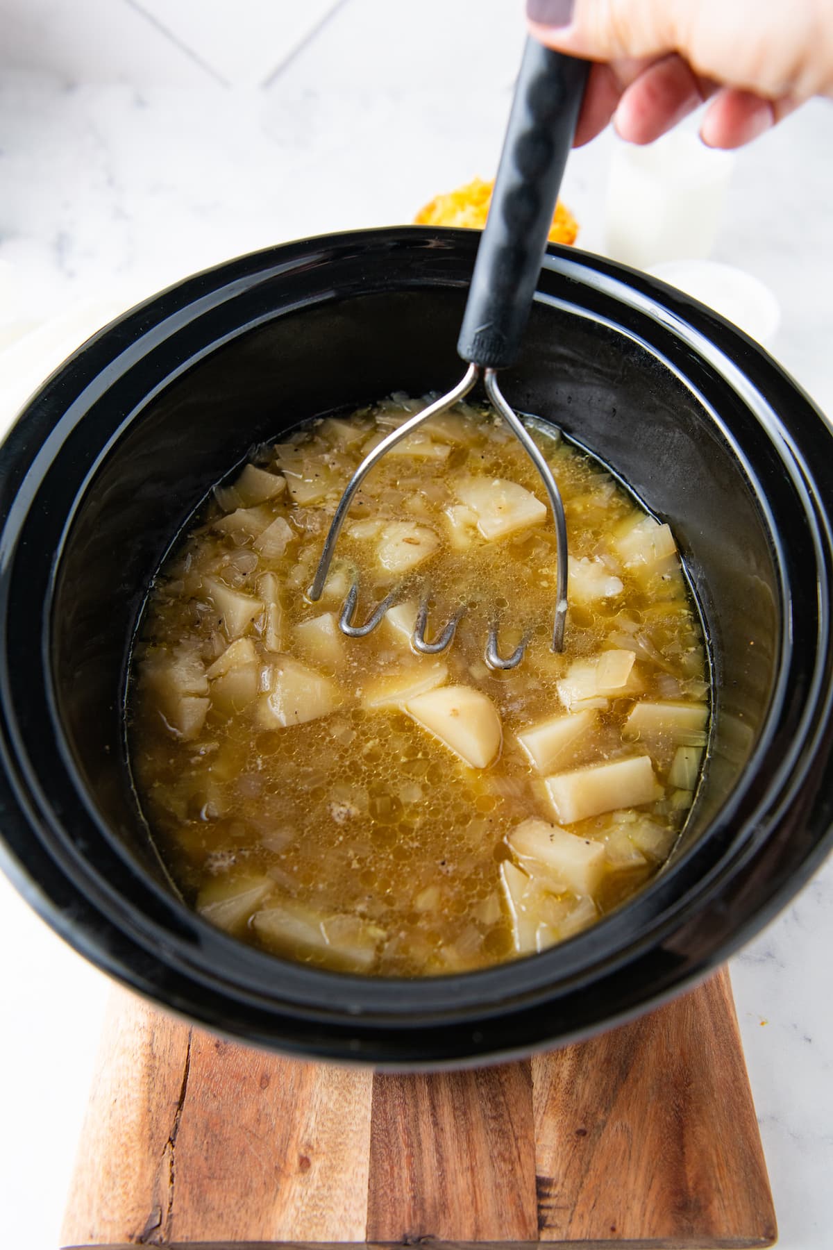 mashing potatoes into soup in a crockpot