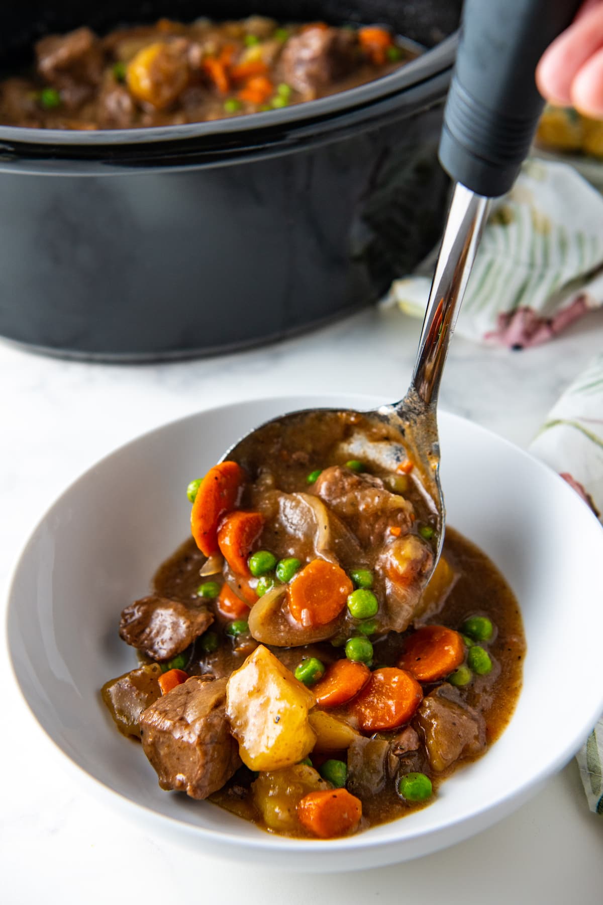 a ladle scooping beef stew into a bowl