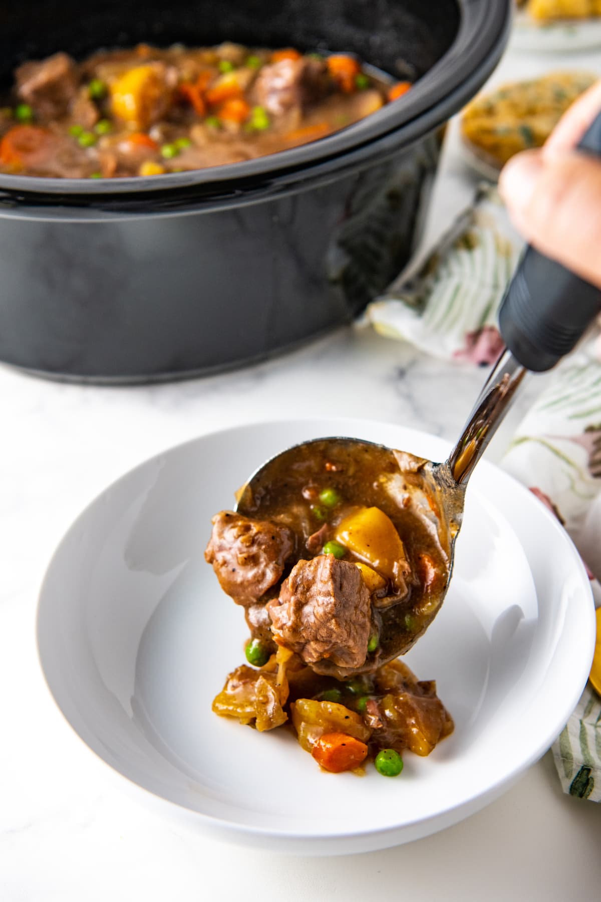 ladling beef stew into a bowl