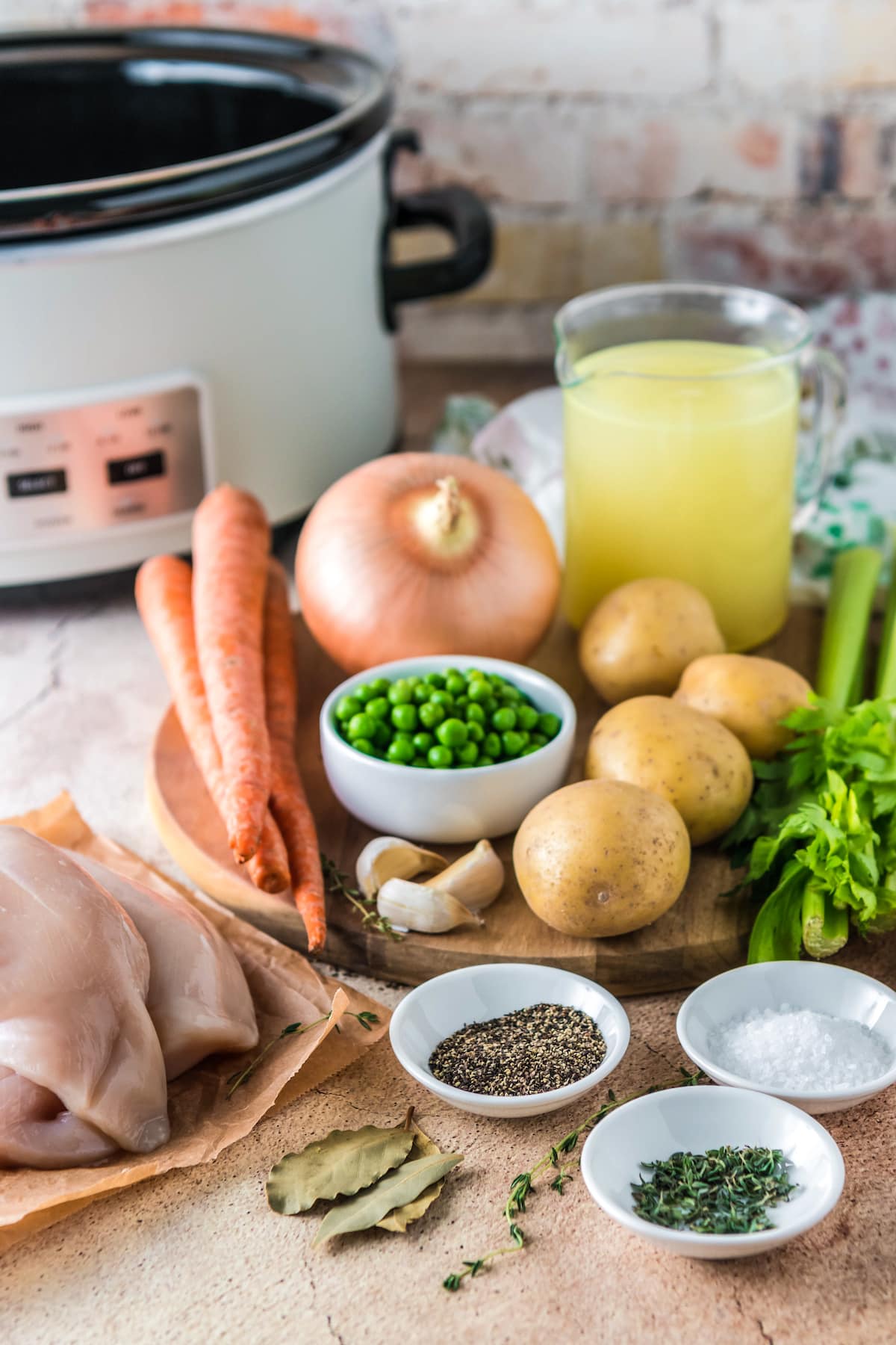 a display of cooking ingredients including carrots, onions. peas, potatoes, chicken breasts, spices, and broth