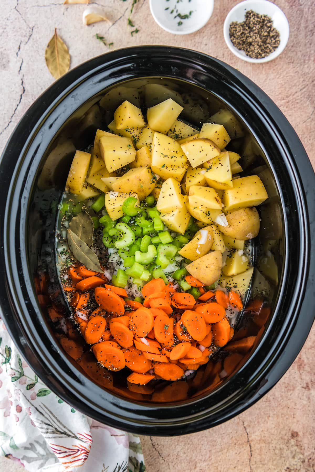 a crockpot with potatoes, celery, and carrots