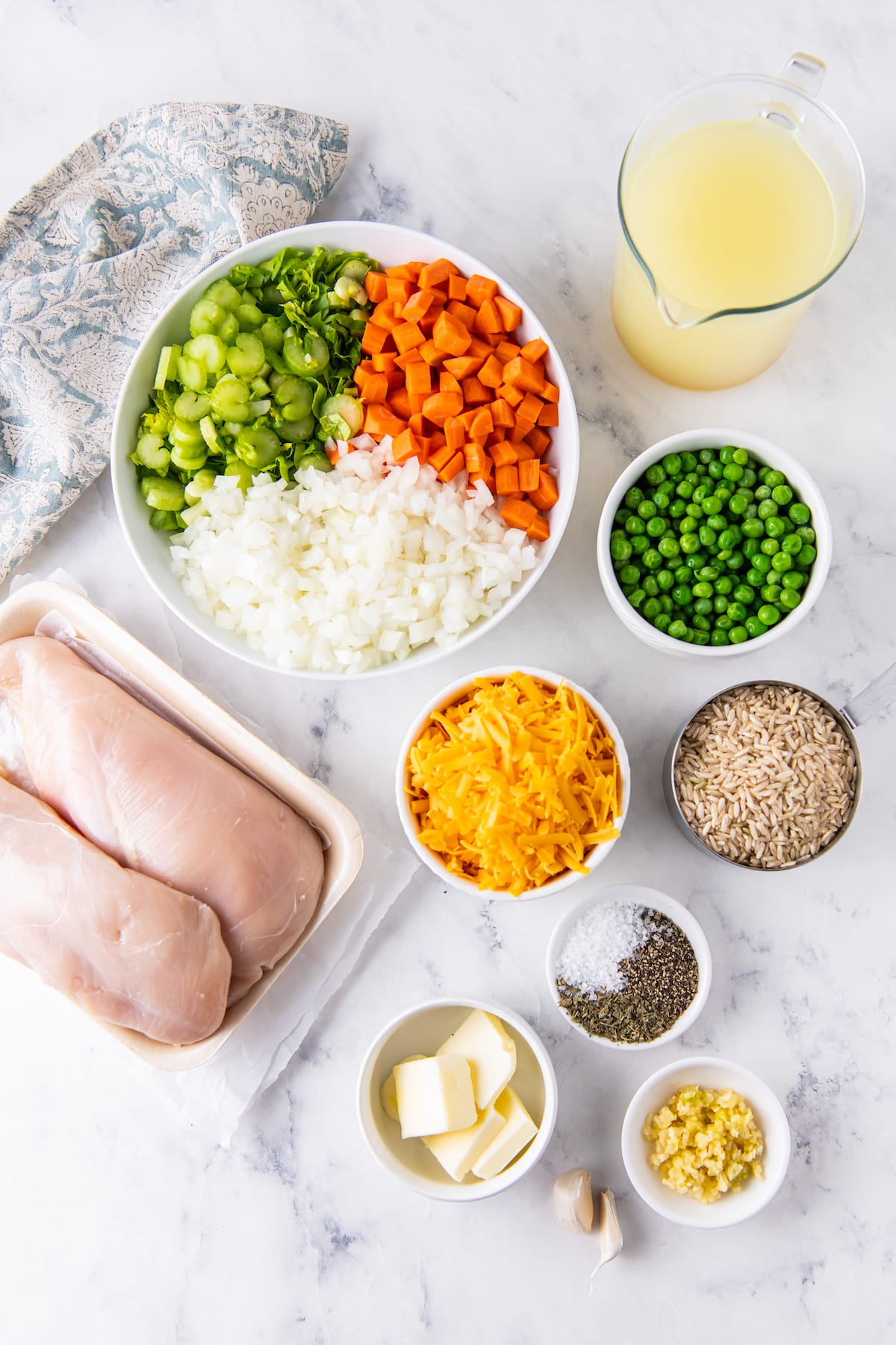 an assortment of dinner ingredients like chicken, vegetables, peas, cheese, rice, seasonings and butter