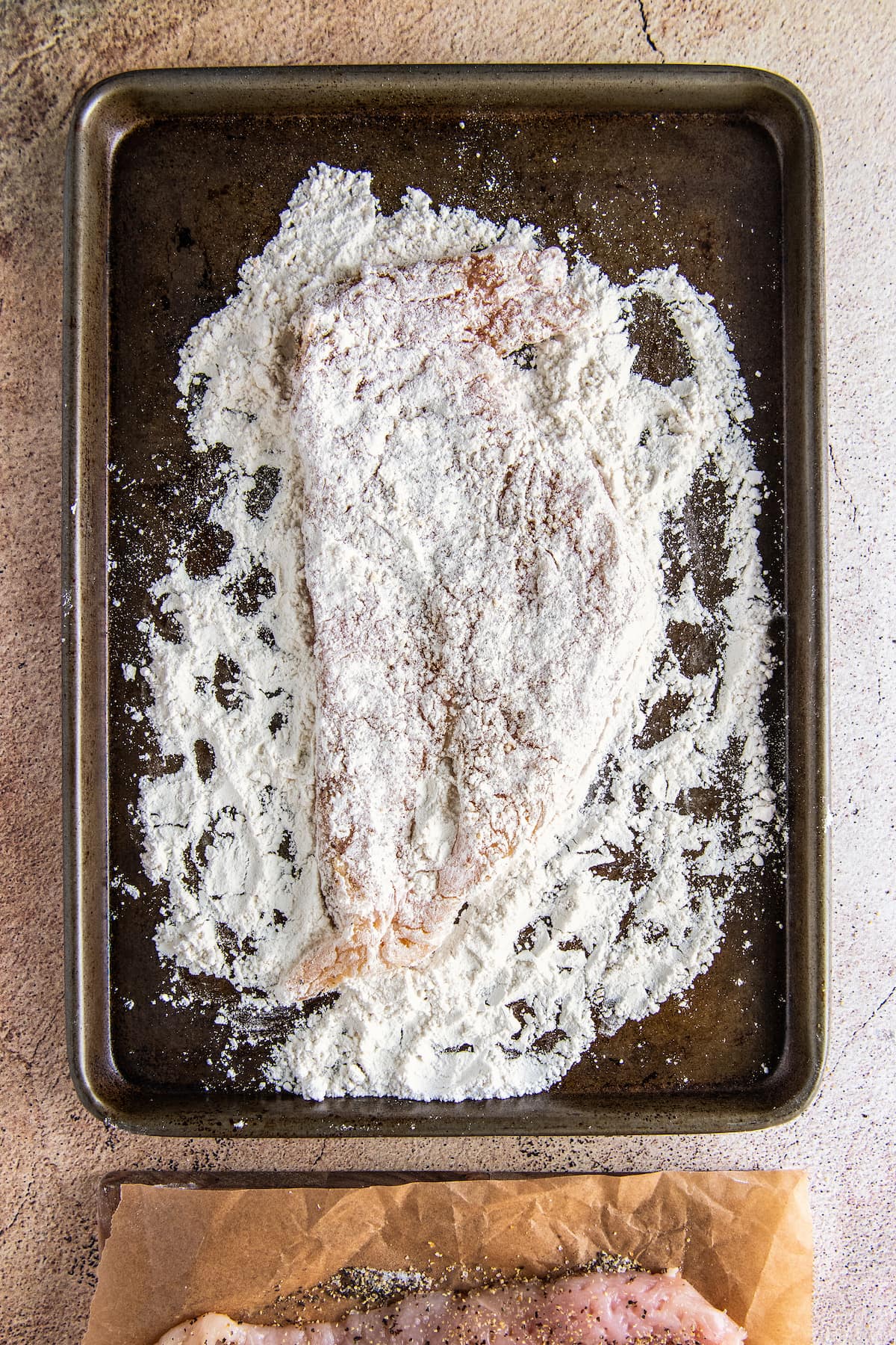 a dredged piece of chicken on a sheet tray