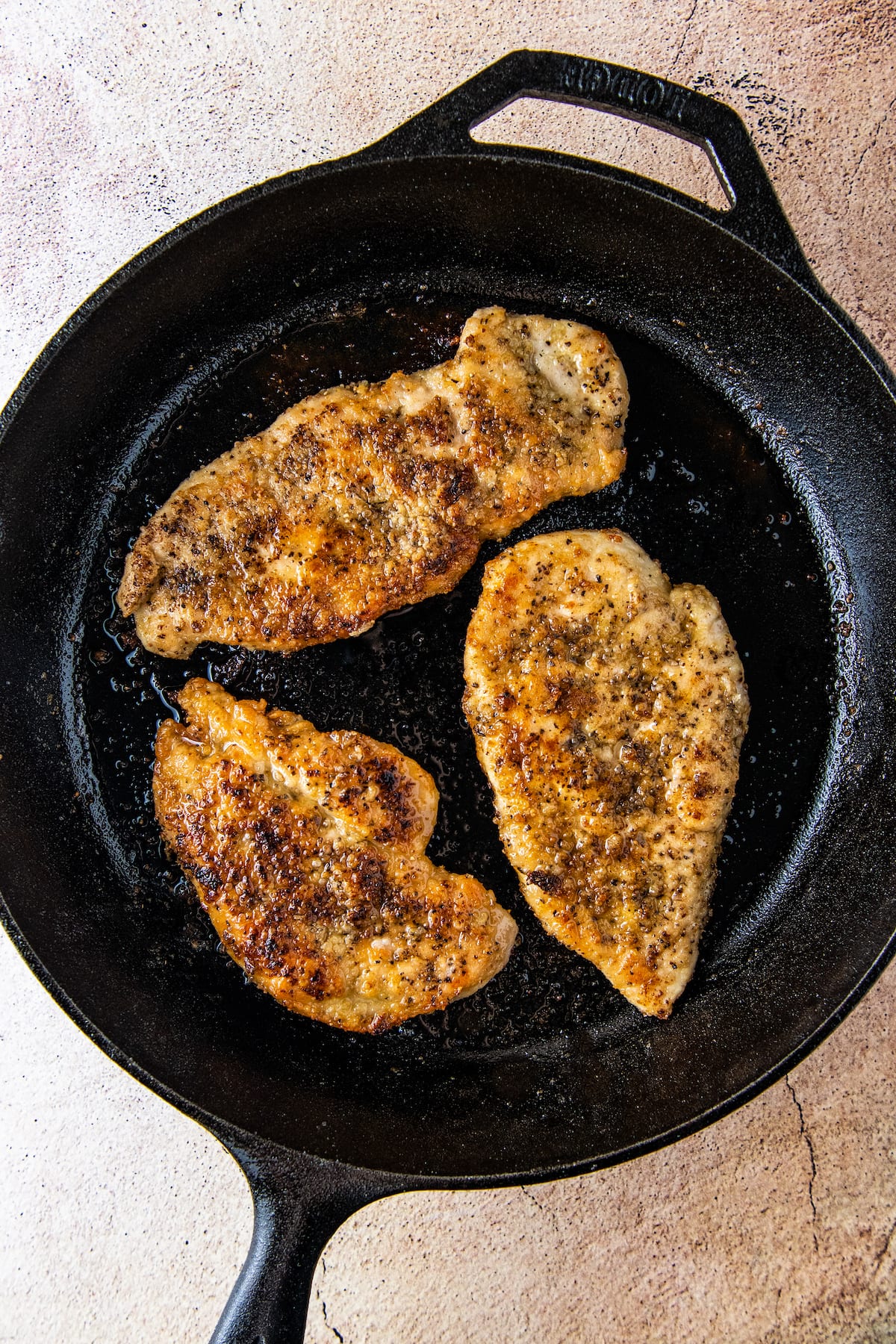 three pan seared chicken breasts in a skillet