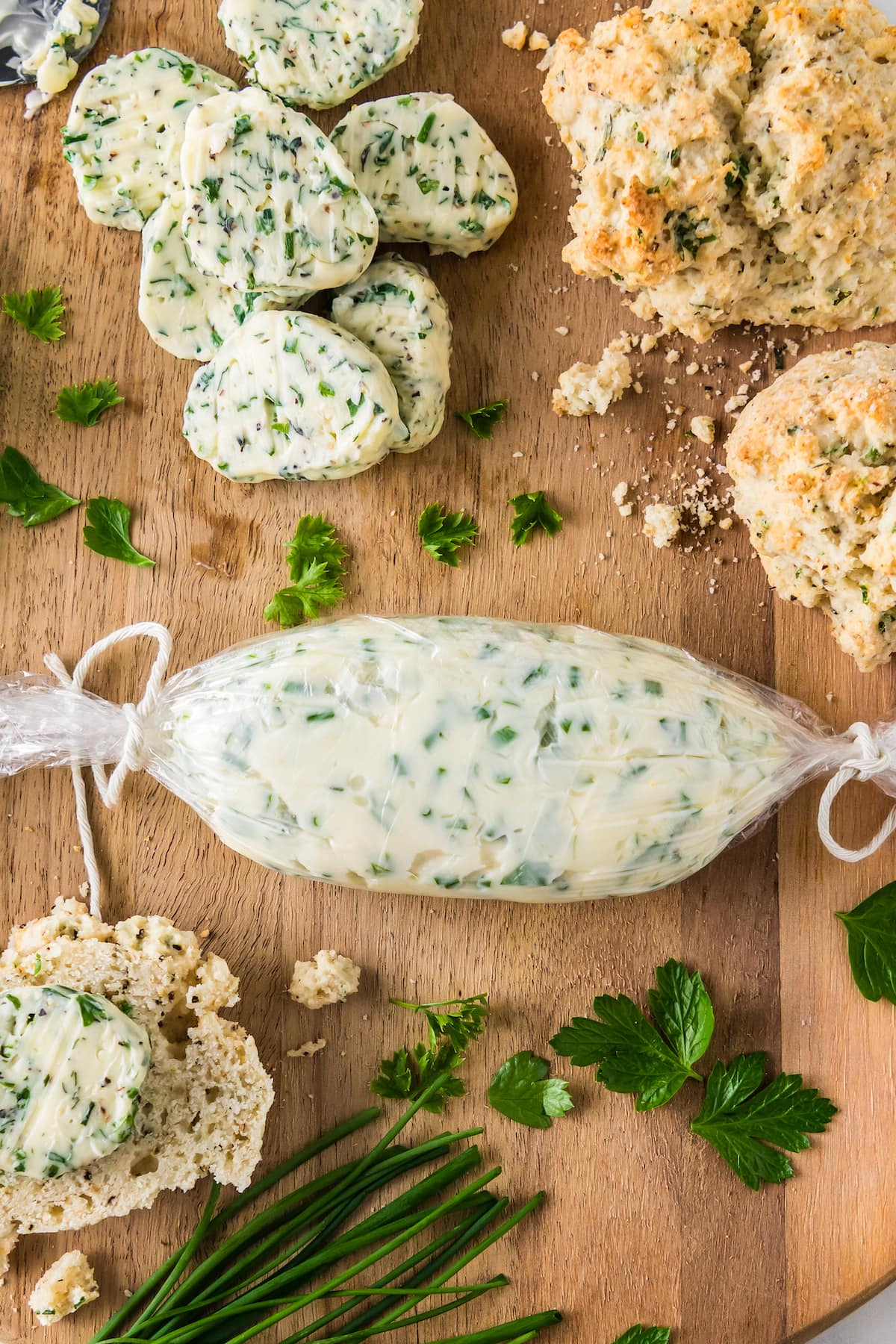 a platter with pads of garlic herb butter, biscuits, and a log of garlic butter