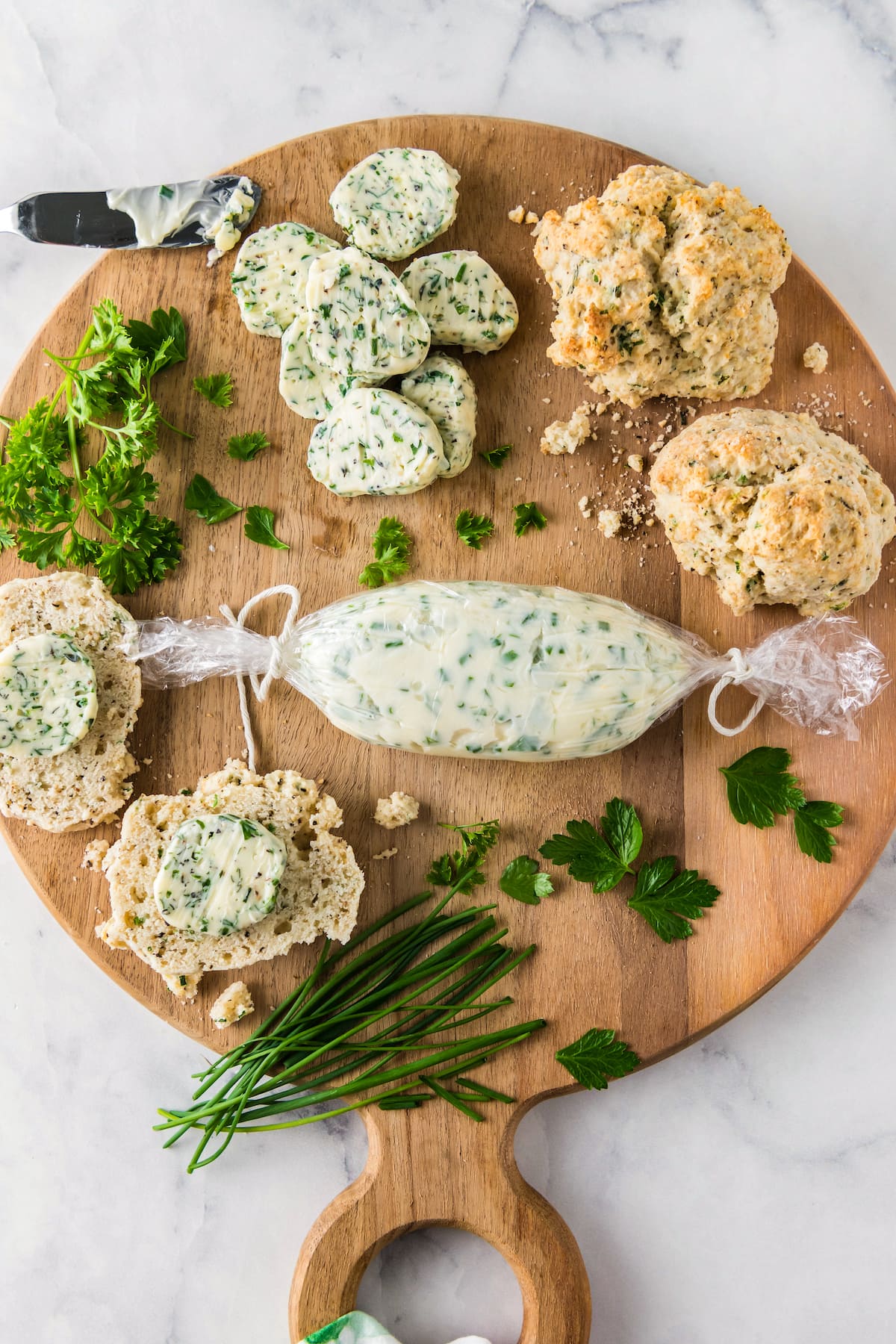 a platter with pads of garlic herb butter, biscuits, and a log of garlic butter