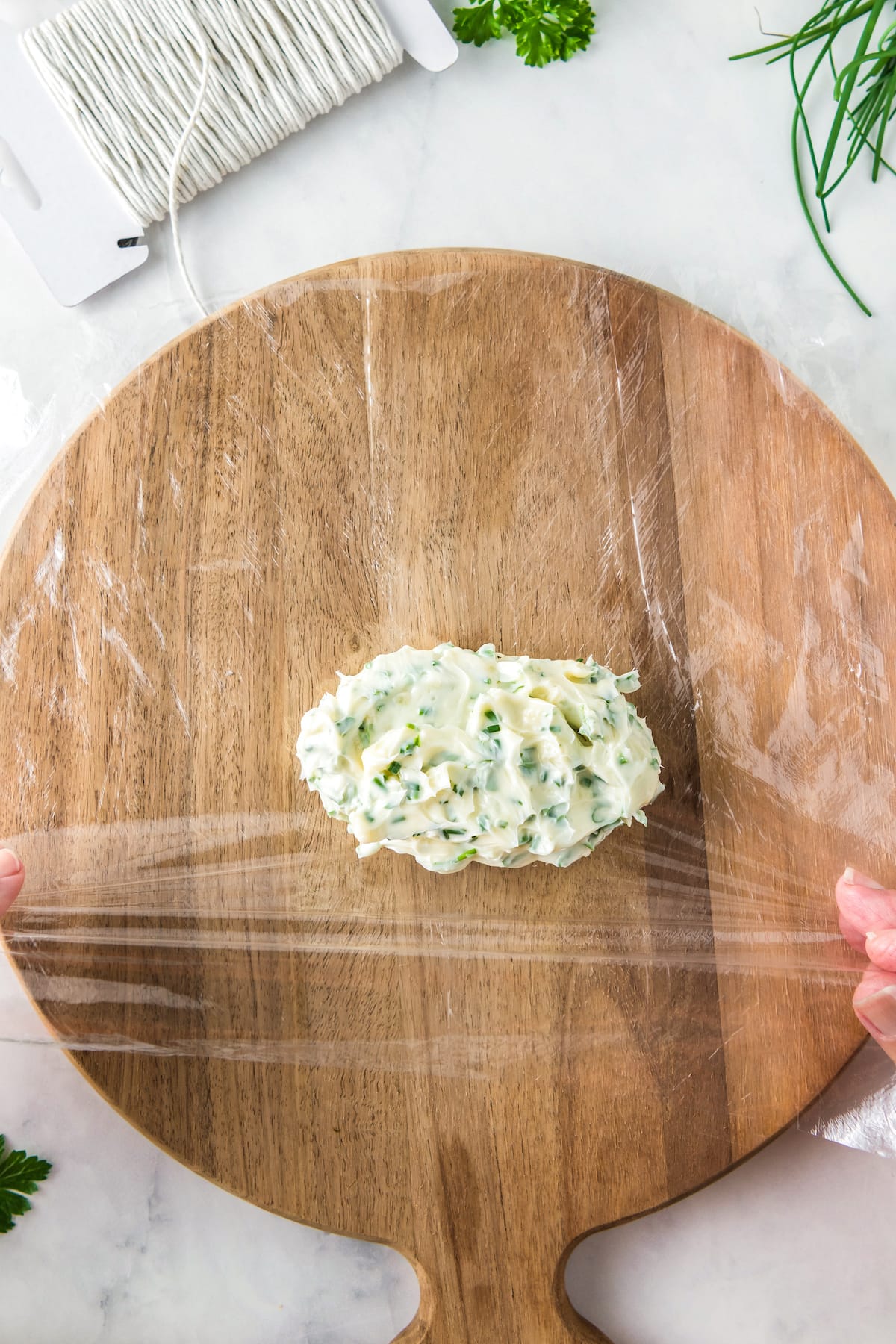 rolling herb garlic butter in plastic wrap