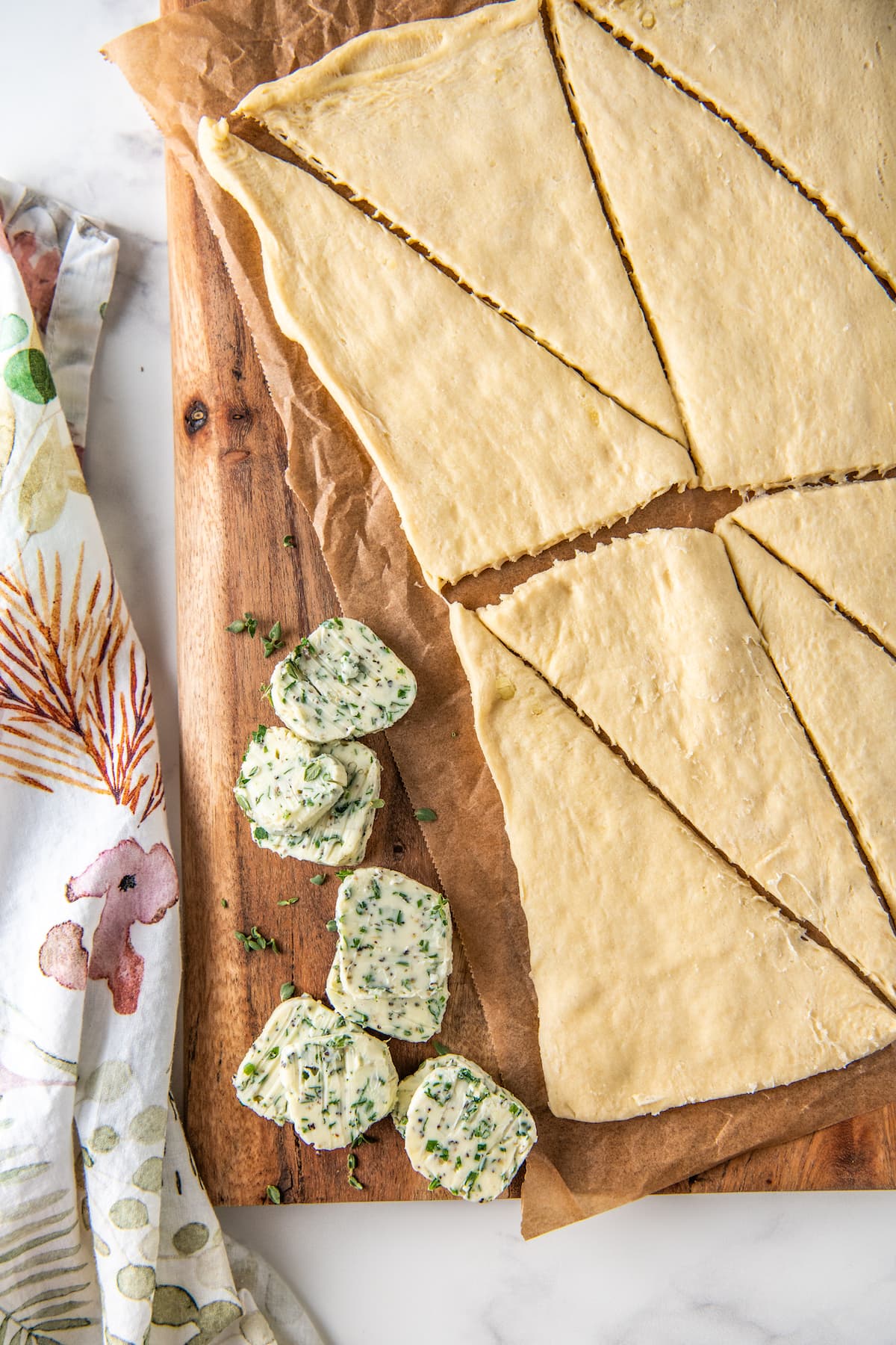 herb butter slices and crescent roll dough on a kitchen work surface