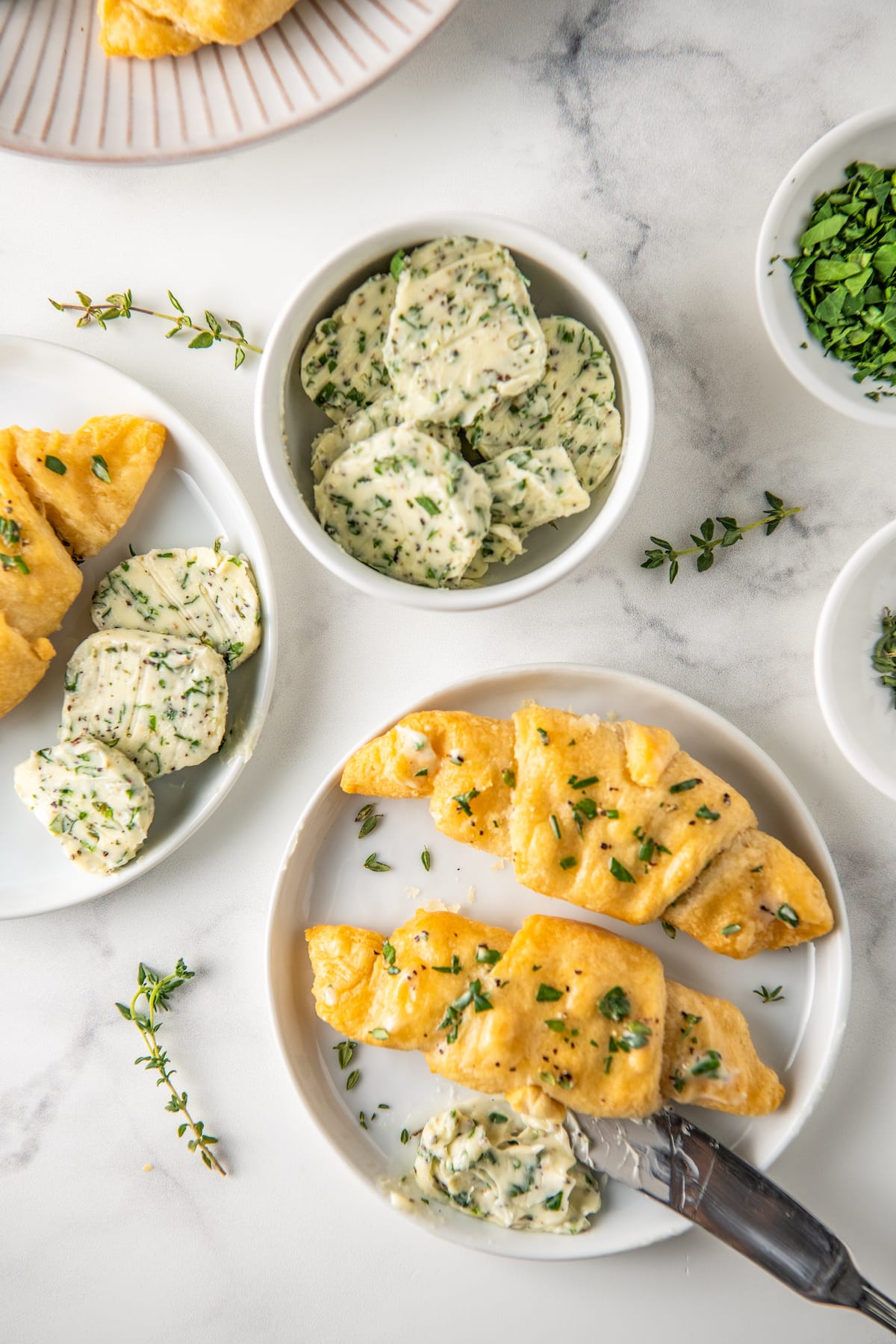 a plate with crescent rolls and butter next to a small bowl with herb butter