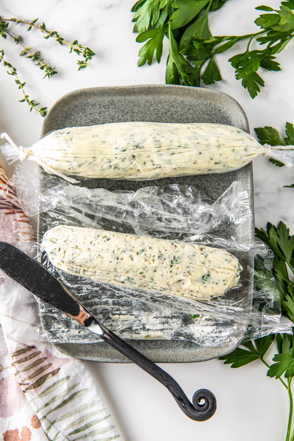two logs of herb butter with plastic wrap