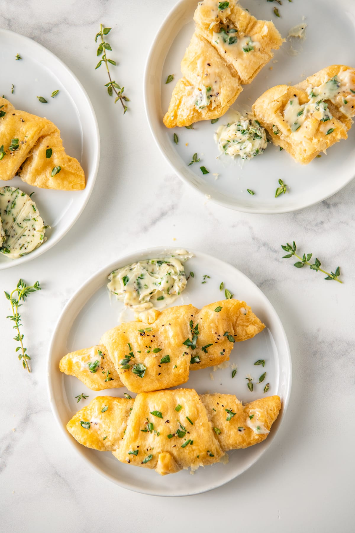 crescent rolls on a plate with slices of herb butter