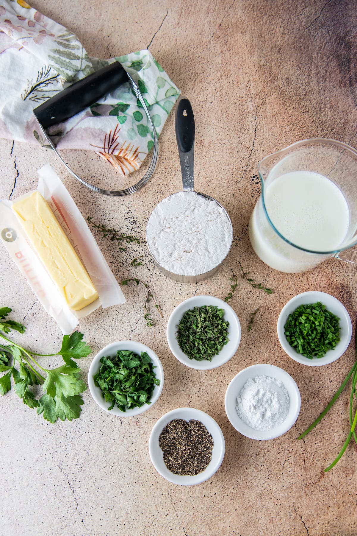 an assortment of cooking ingredients like butter, fresh herbs, cream, and flour