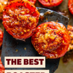 Two roasted tomatoes with garlic on a spatula.