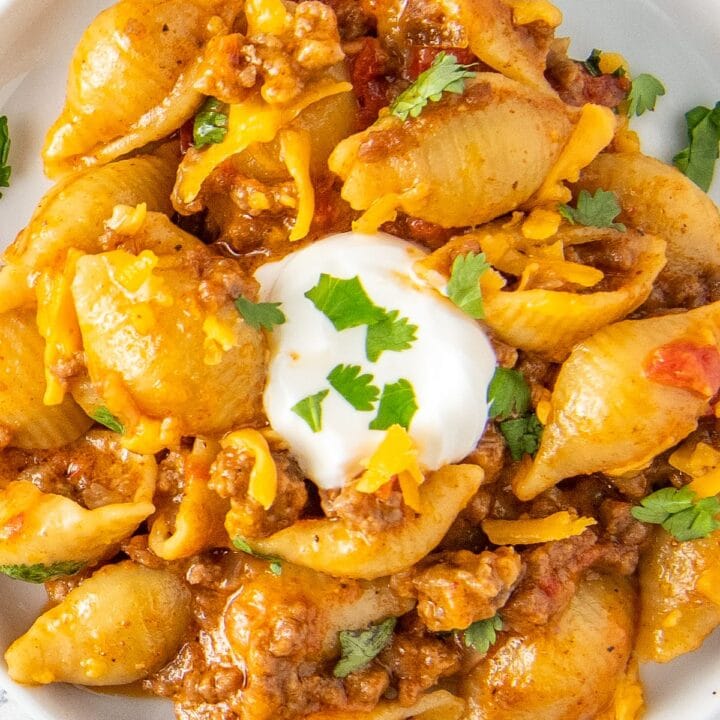 close up of a taco pasta dish with shells, tomato sauce, ground beef, and cheese