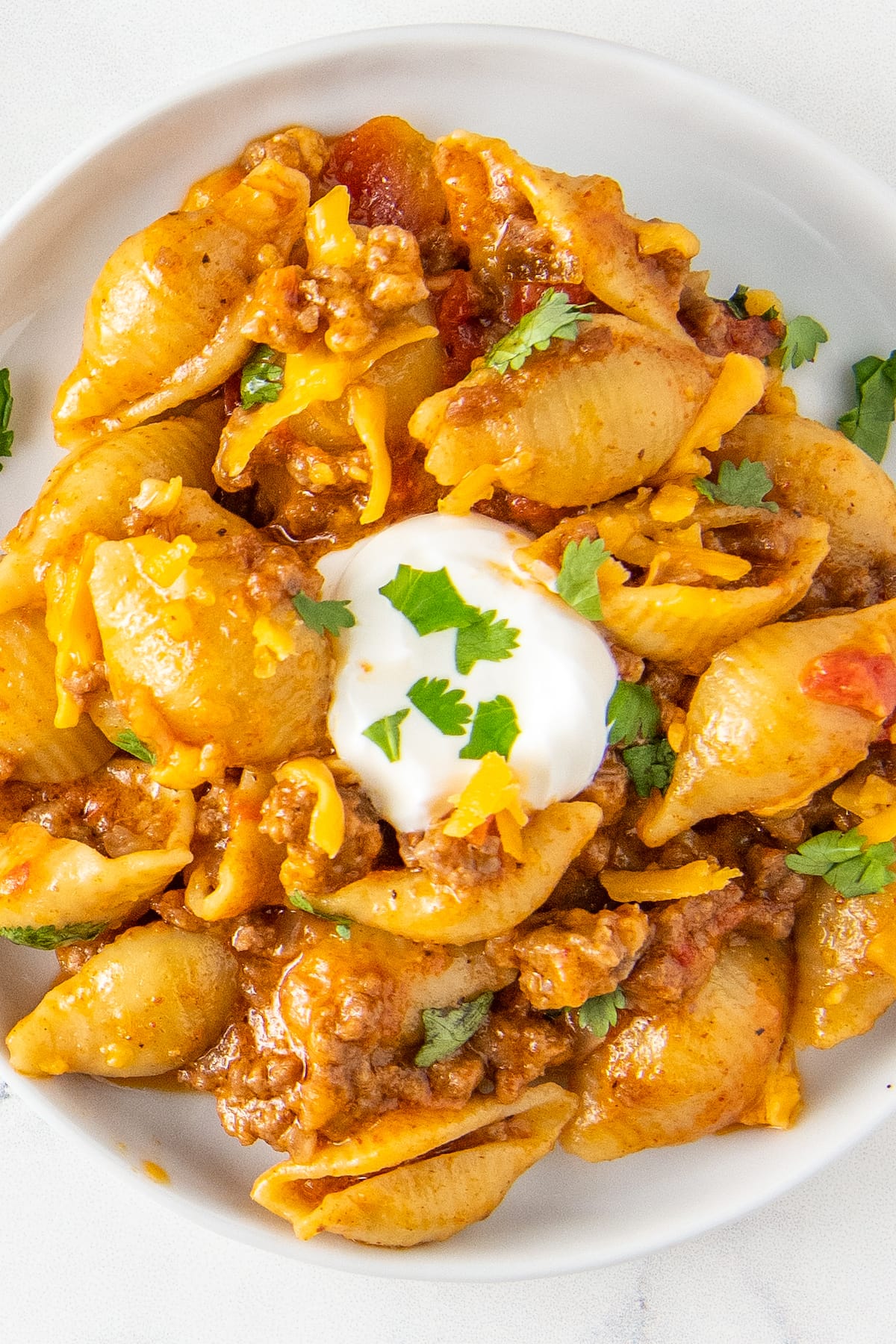 close up of a taco pasta dish with shells, tomato sauce, ground beef, and cheese