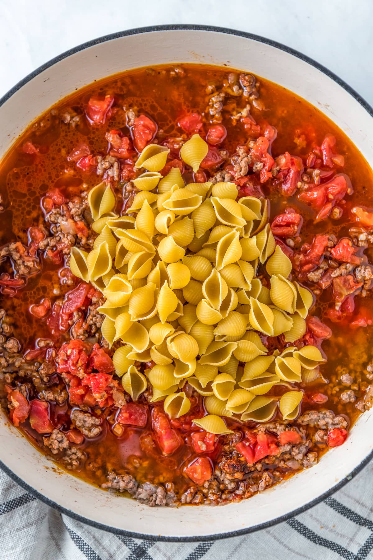 dried pasta in a pot with ground beef and tomato sauce