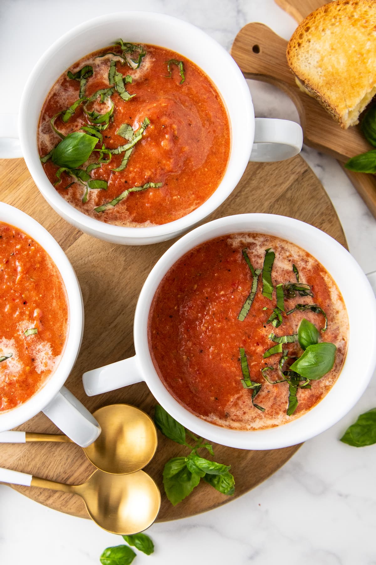 three bowls of tomato soup with basil