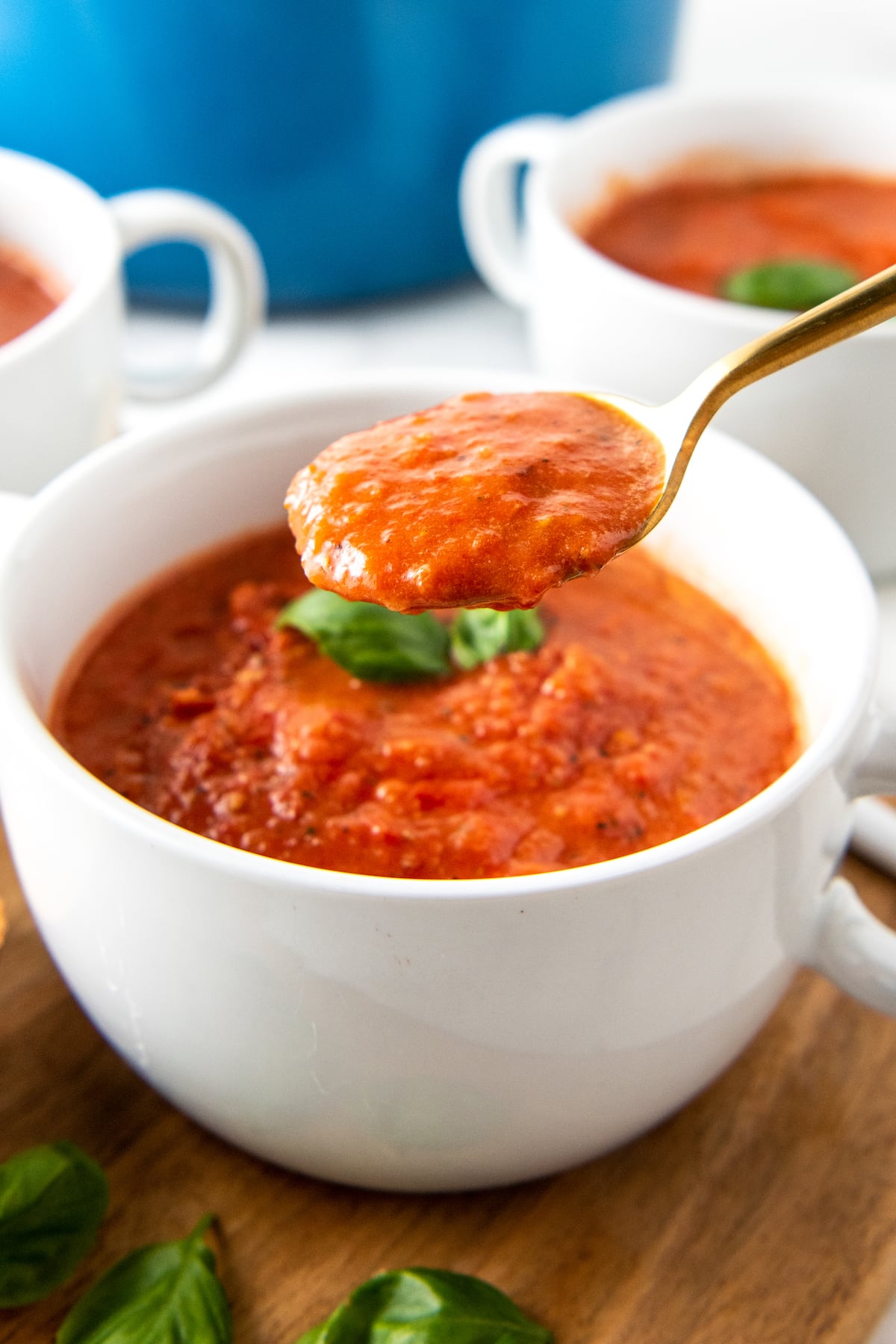 a bowl of tomato basil soup with a spoon taking a bite out