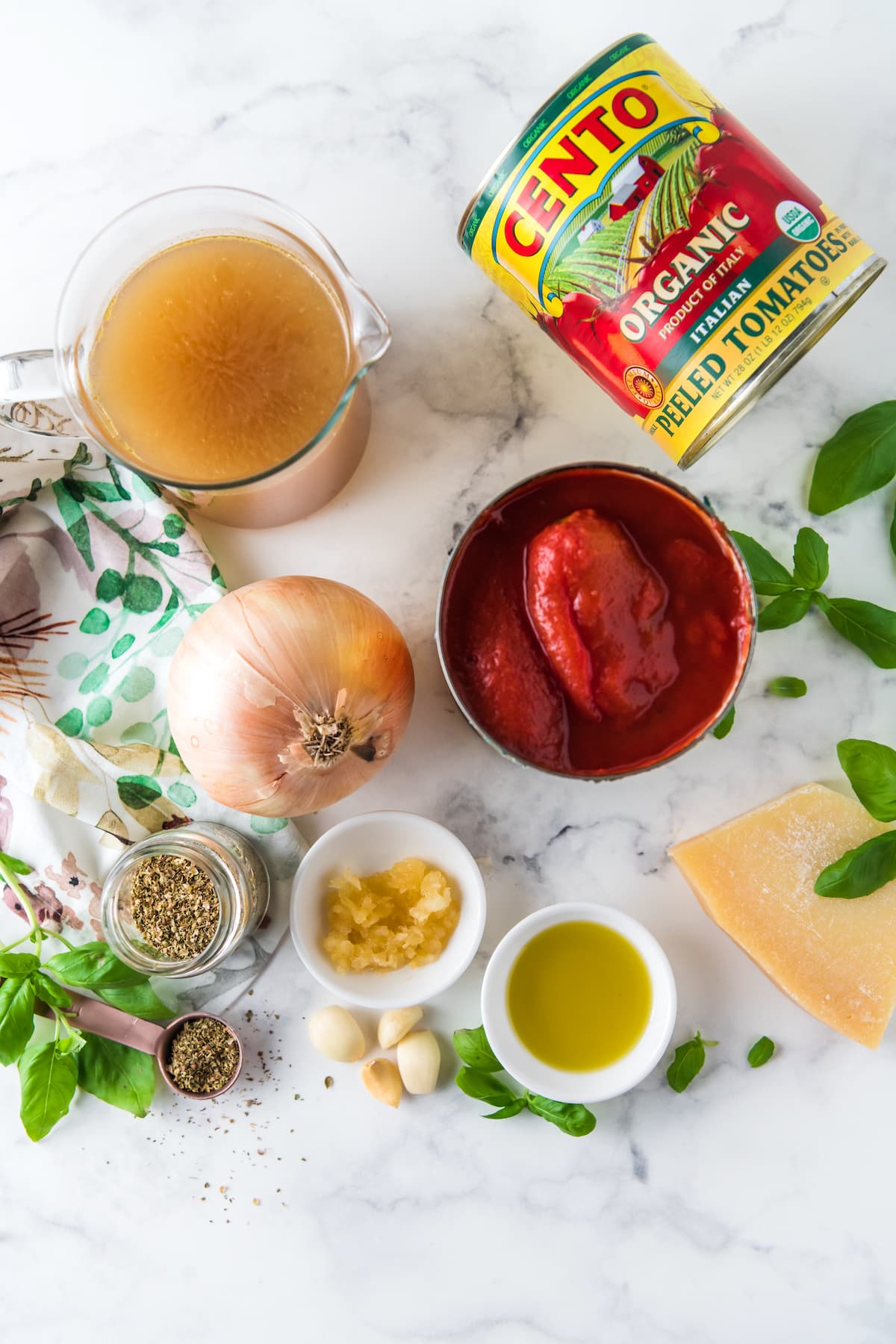 ingredients to make tomato soup like canned tomatoes, onions, stock, olive oil, parmesan, garlic, basil, and seasonings