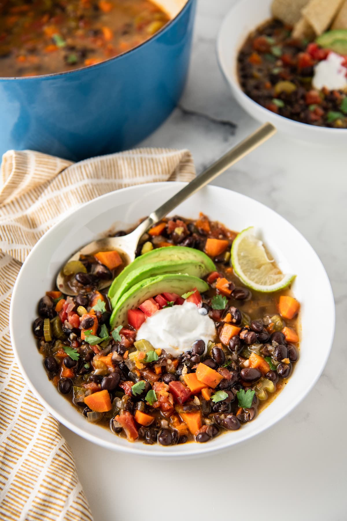 carrot black bean soup with avocado, tomato, sour cream, and lime garnish