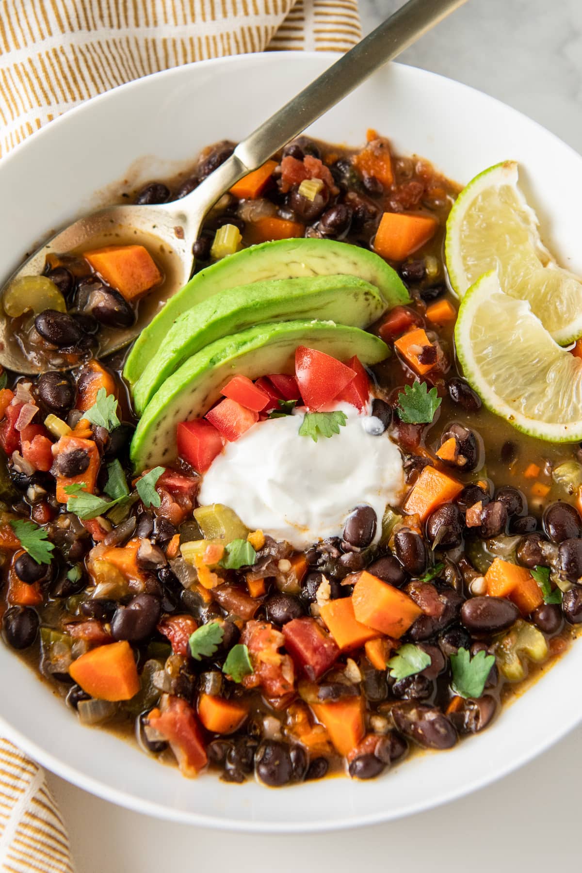 carrot black bean soup with avocado, tomato, sour cream, and lime garnish