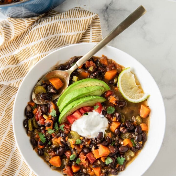 carrot black bean soup with avocado, tomato, sour cream, and lime garnish