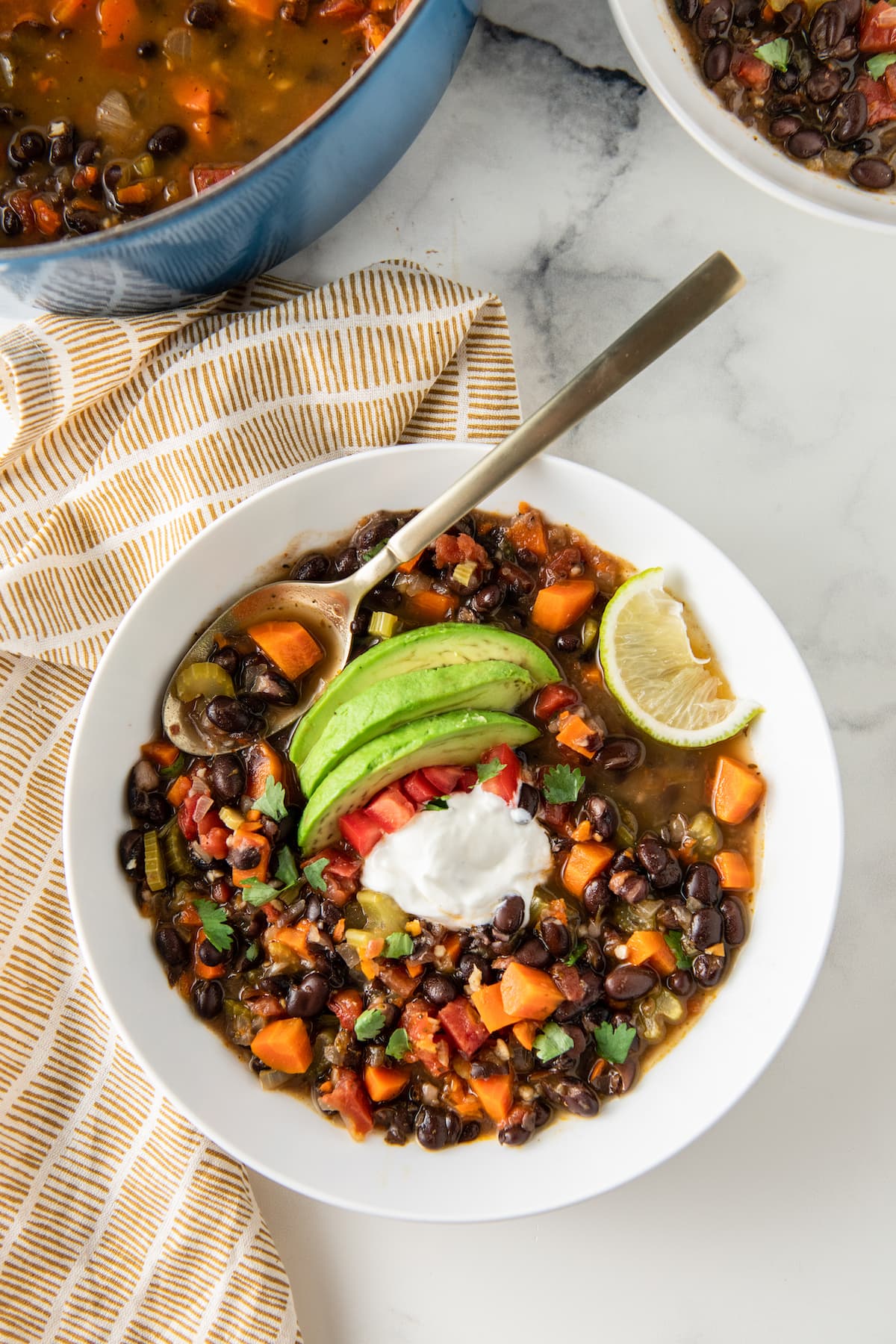 carrot black bean soup with avocado, tomato, sour cream, and lime garnish