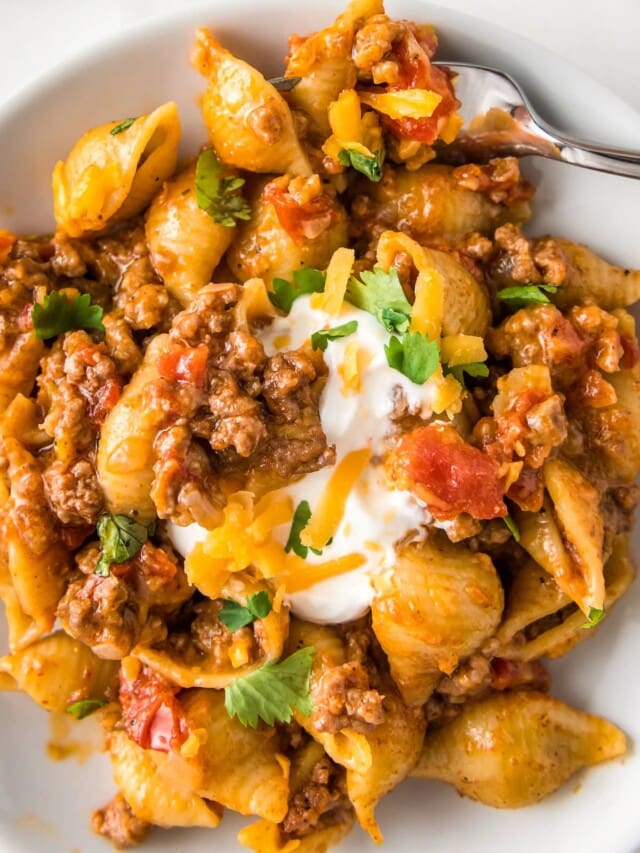 close up of a taco pasta dish with shells, tomato sauce, ground beef, and cheese