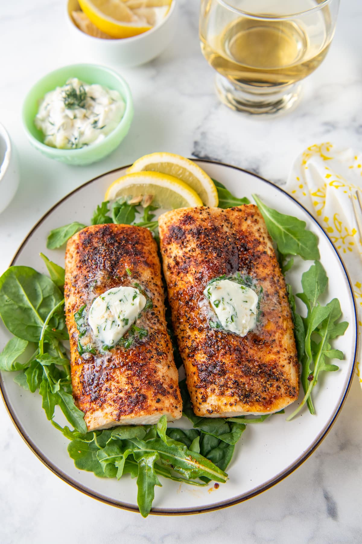 Leafy arugula is placed all around and under the cooked fish on a round plate. 